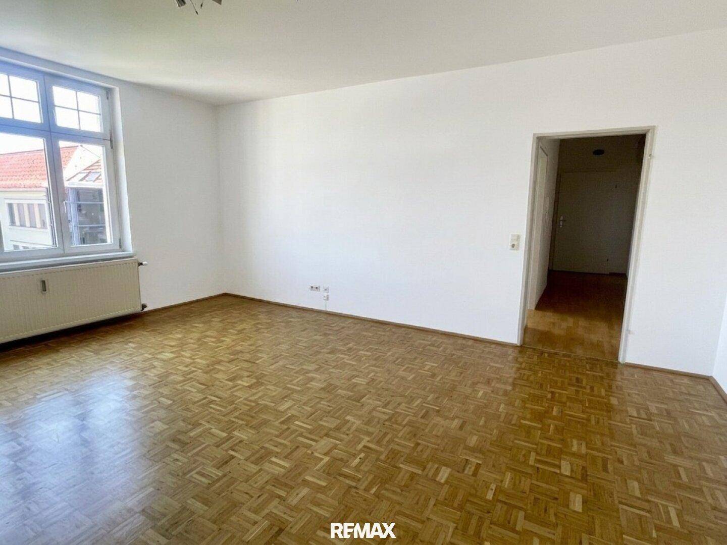 Leeres Zimmer mit Parkettboden und Zugang zu einem weiteren Raum, ideal für flexible Nutzung.