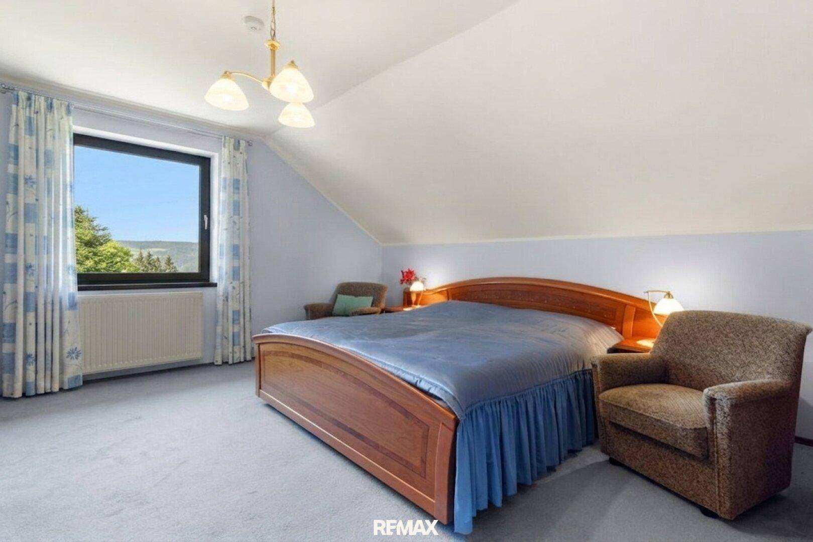 Helles Schlafzimmer im Dachgeschoss mit Teppichboden und schrägen Wänden.