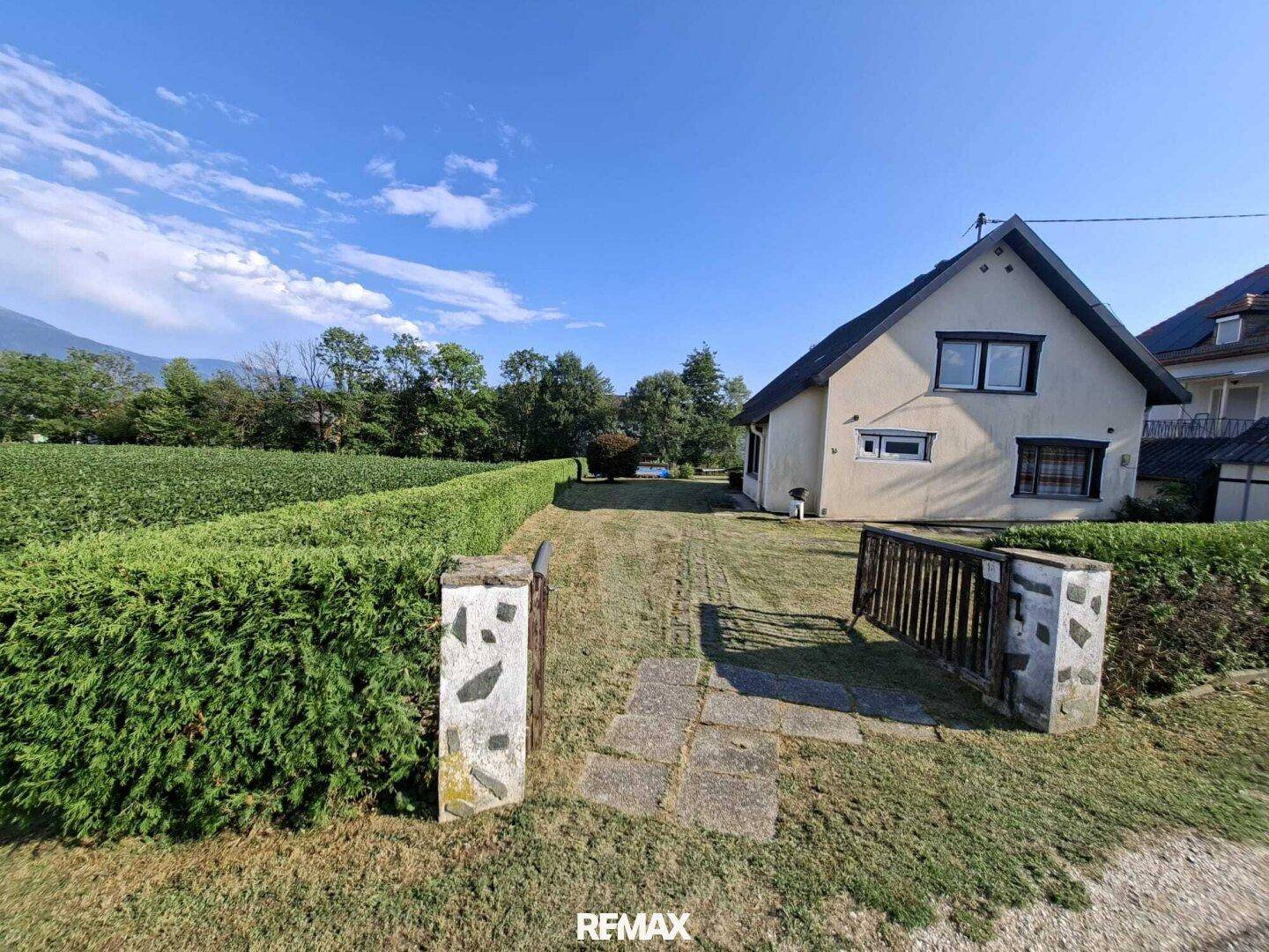 Eingangsbereich des Grundstücks mit gepflegter Hecke und Zufahrt zum Haus.