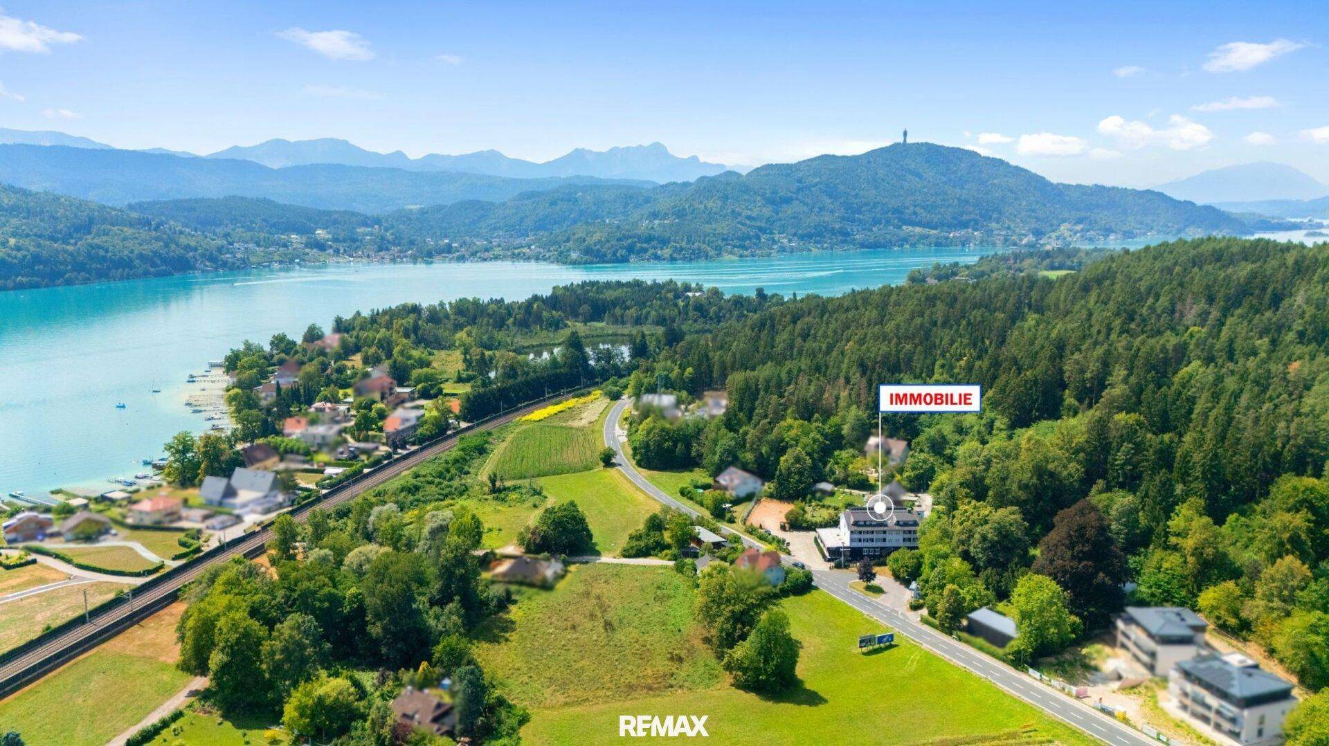 Weitläufige Luftaufnahme der Immobilie eingebettet in die Natur mit See und Bergen.