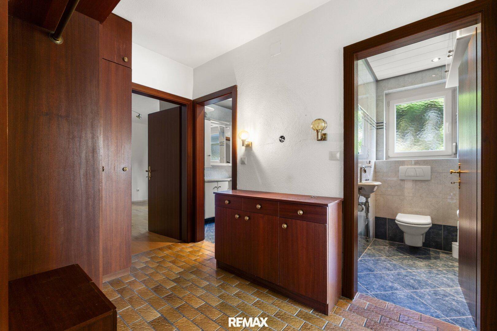 Flur mit Holzmöbeln und Zugang zu einem Badezimmer mit Fenster.