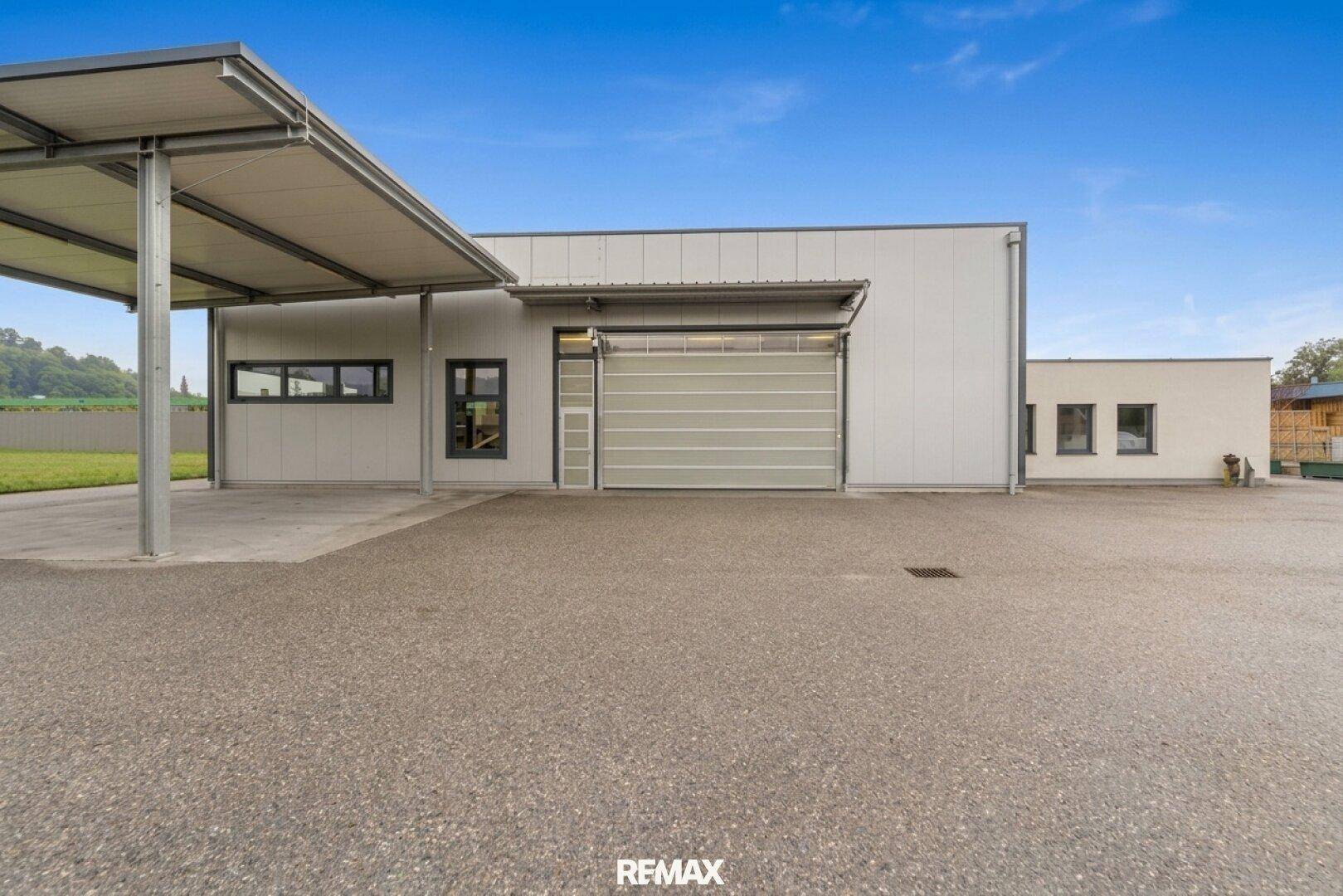 Vorderansicht des modernen Gewerbegebäudes mit Carport und großem Rolltor.