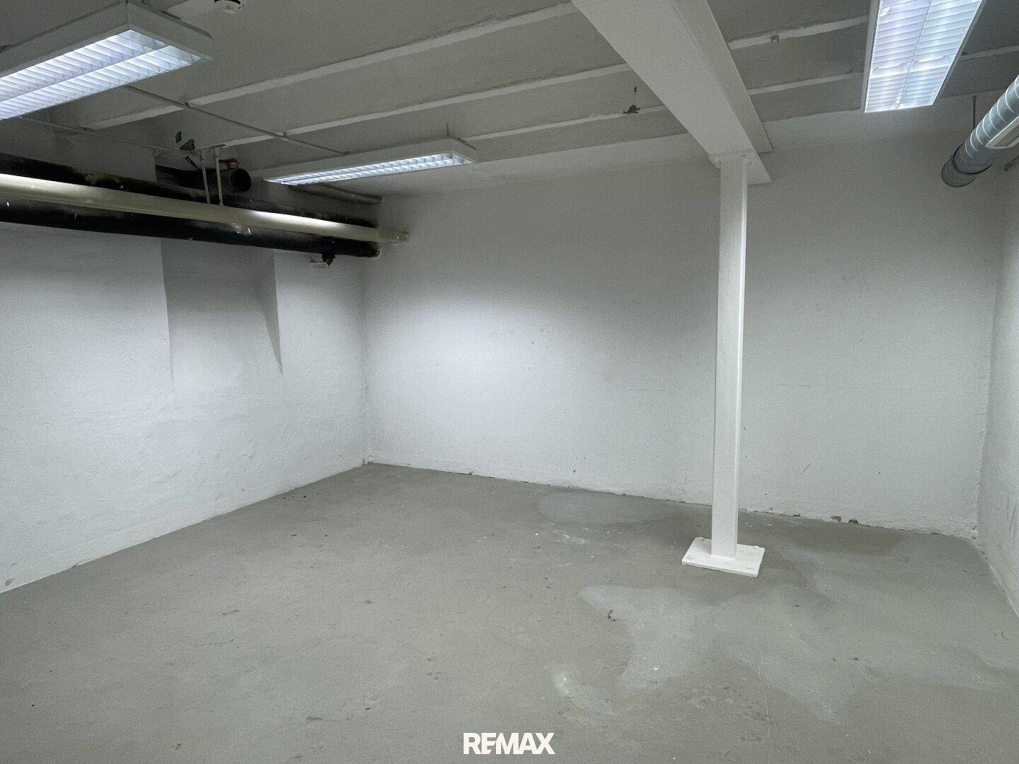 Geräumiger Kellerraum mit Betonboden, tragenden Säulen und Deckenbeleuchtung.