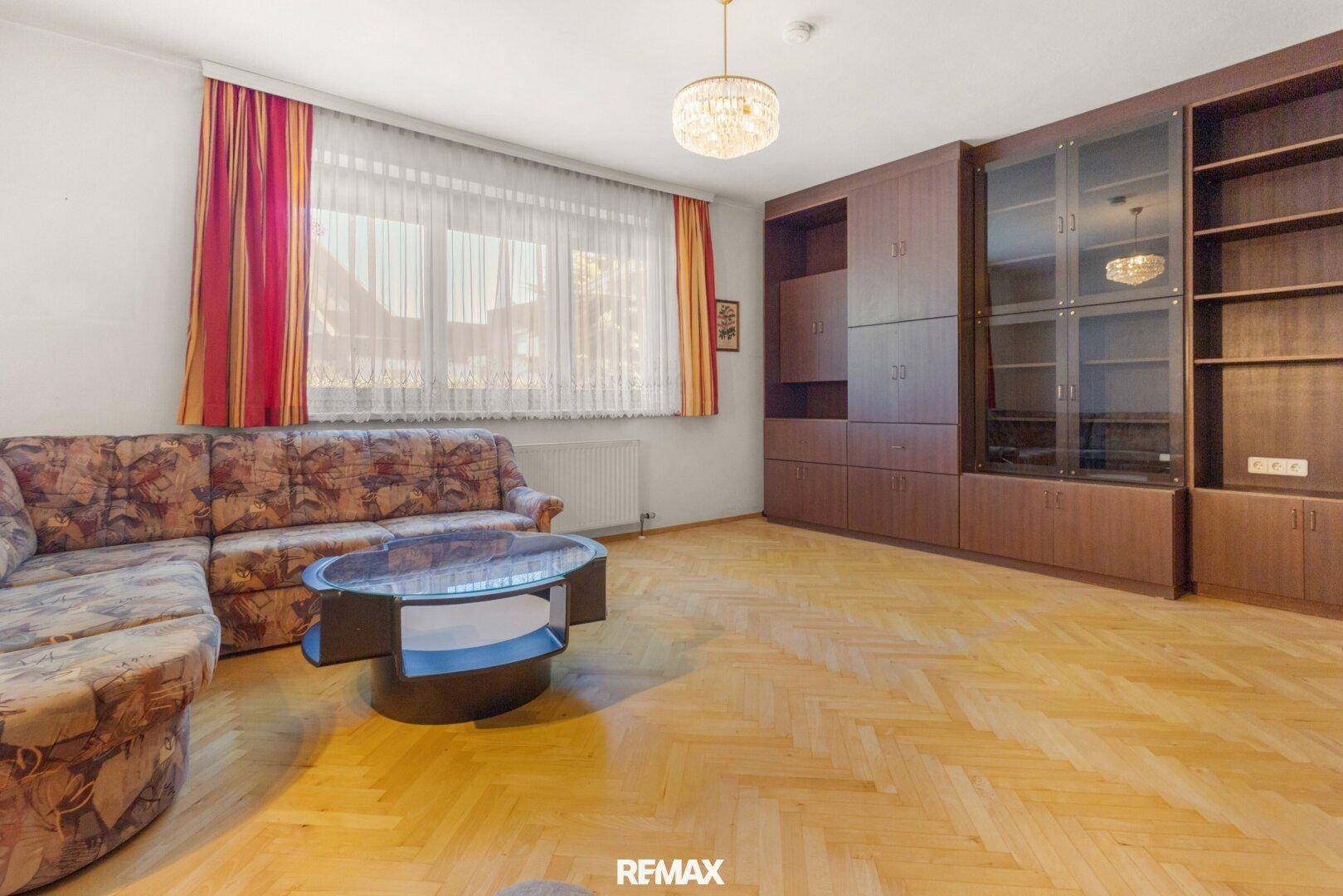 Geräumiges Wohnzimmer mit Parkettboden, großer Couch und Einbauschränken.