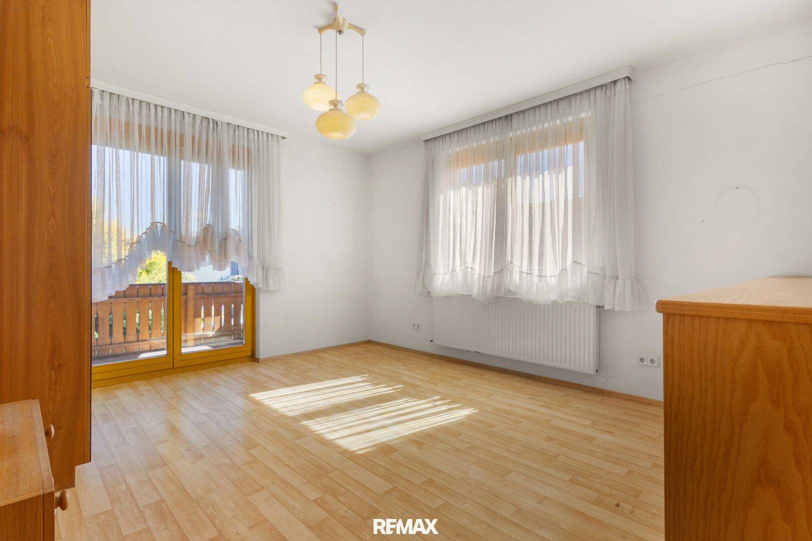 Helles Schlafzimmer mit Holzboden und Zugang zum Balkon, unmöbliert.