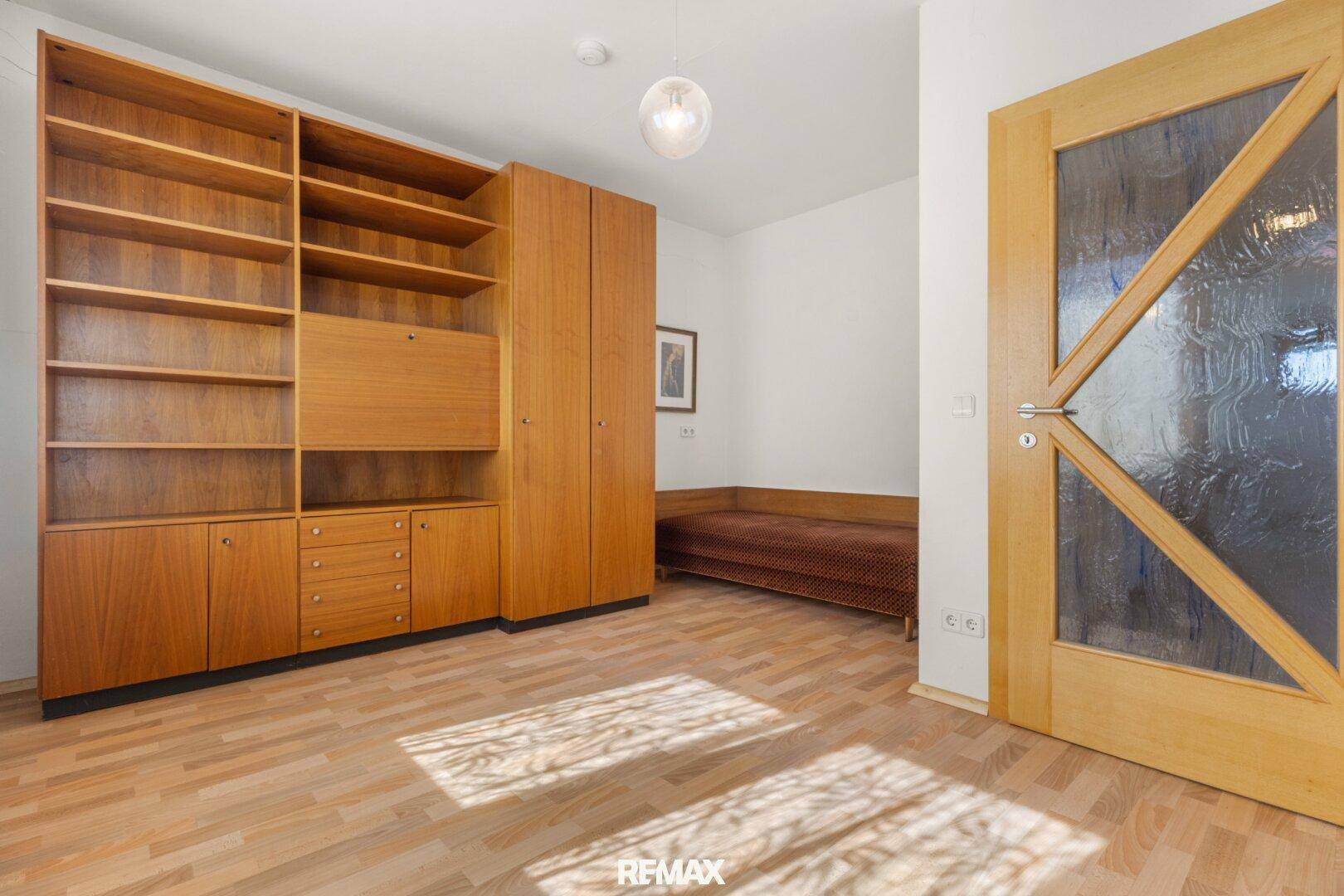 Zimmer mit Holzboden, Einbauschränken und Tagesbett, ideal als Gästezimmer.