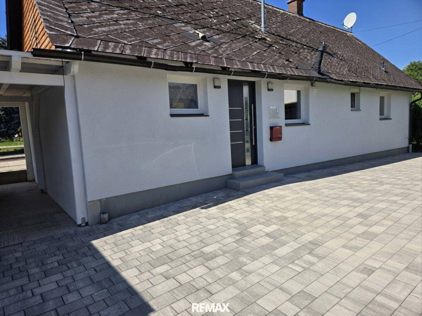 Haus mit gepflastertem Vorhof und Parkmöglichkeiten.