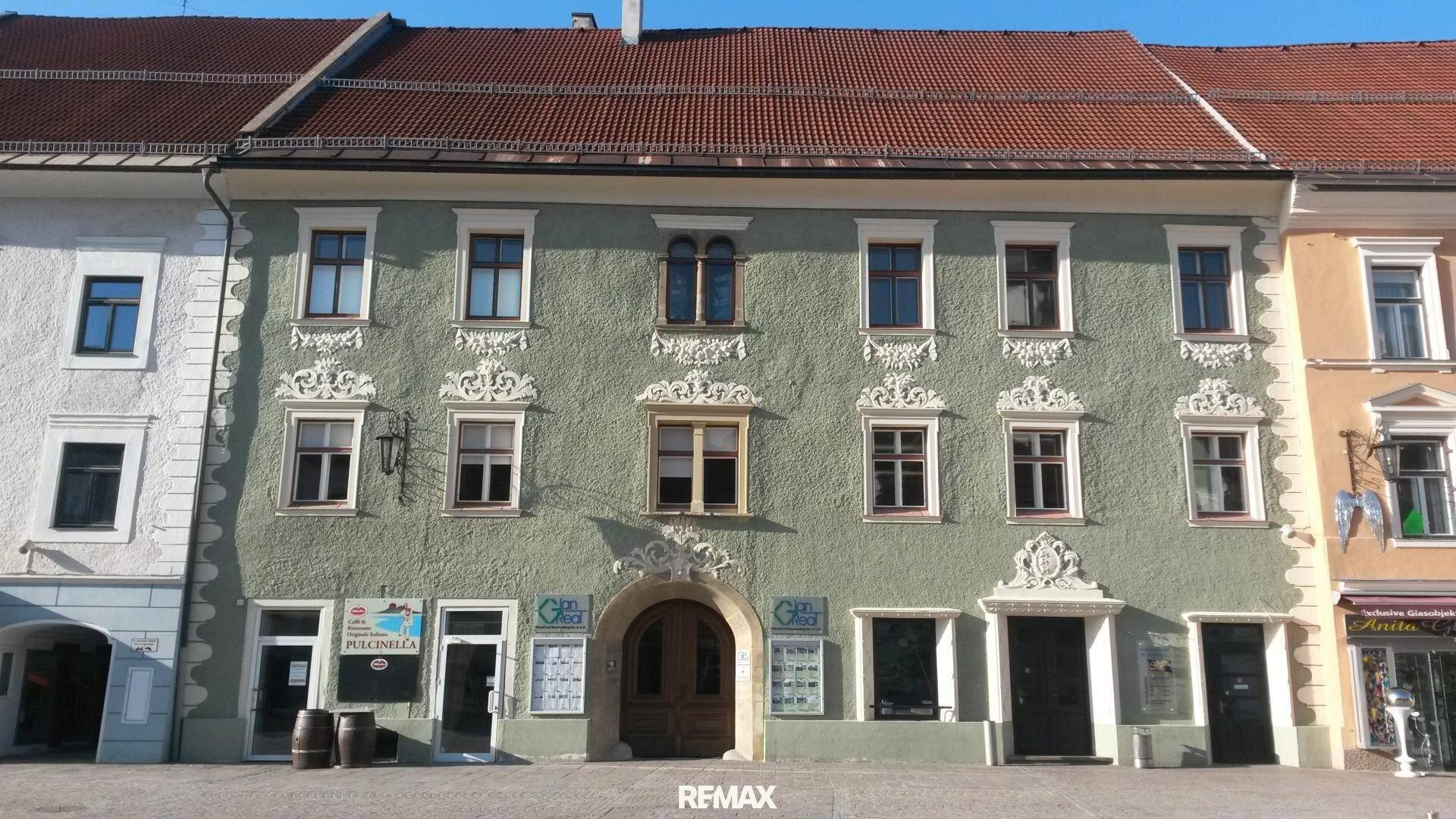 Detailansicht einer historischen Fassade mit dekorativen Elementen und mehreren Fenstern.