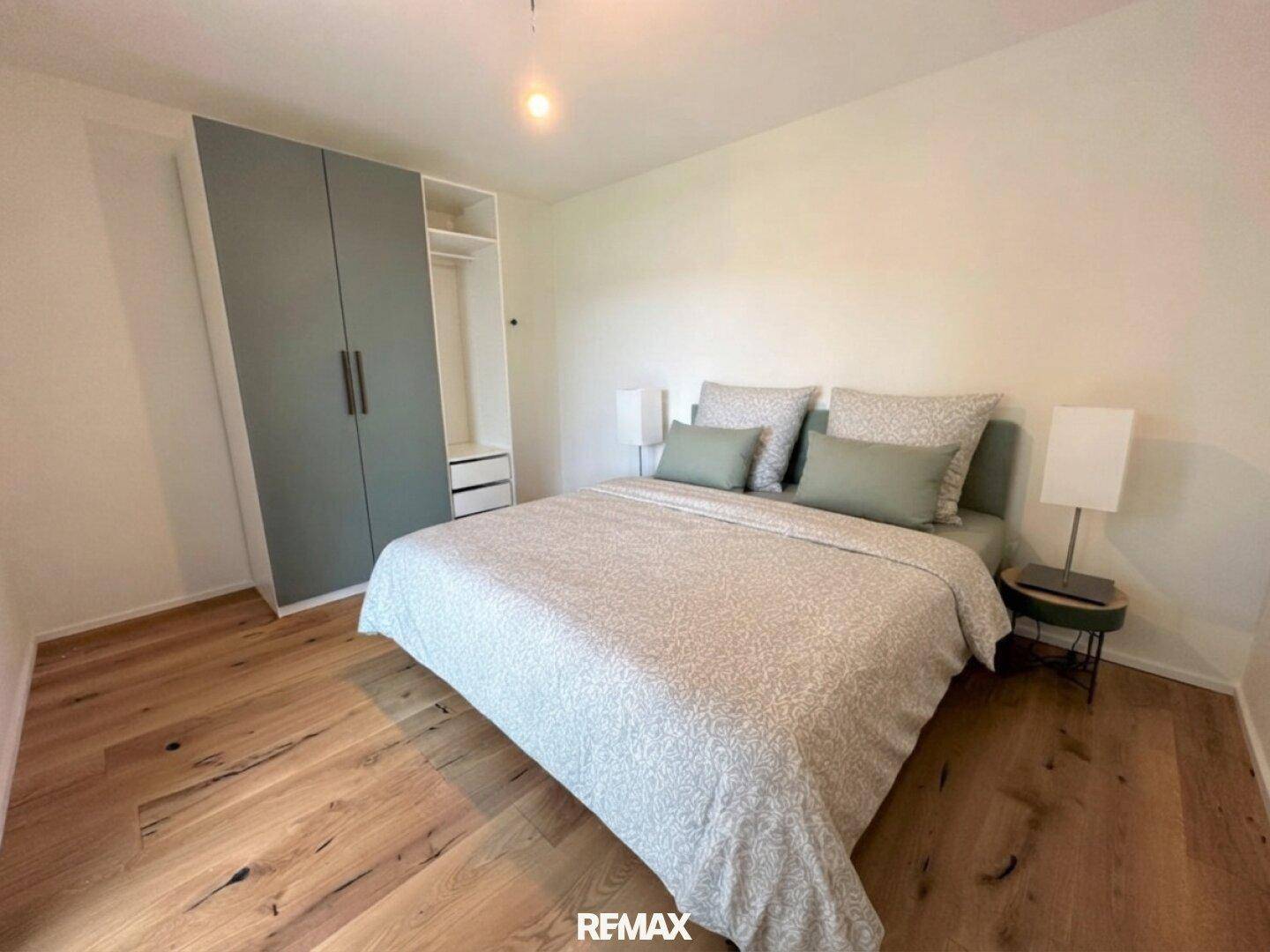 Schlafzimmer mit Holzboden, Doppelbett und integriertem Kleiderschrank in modernem Design.