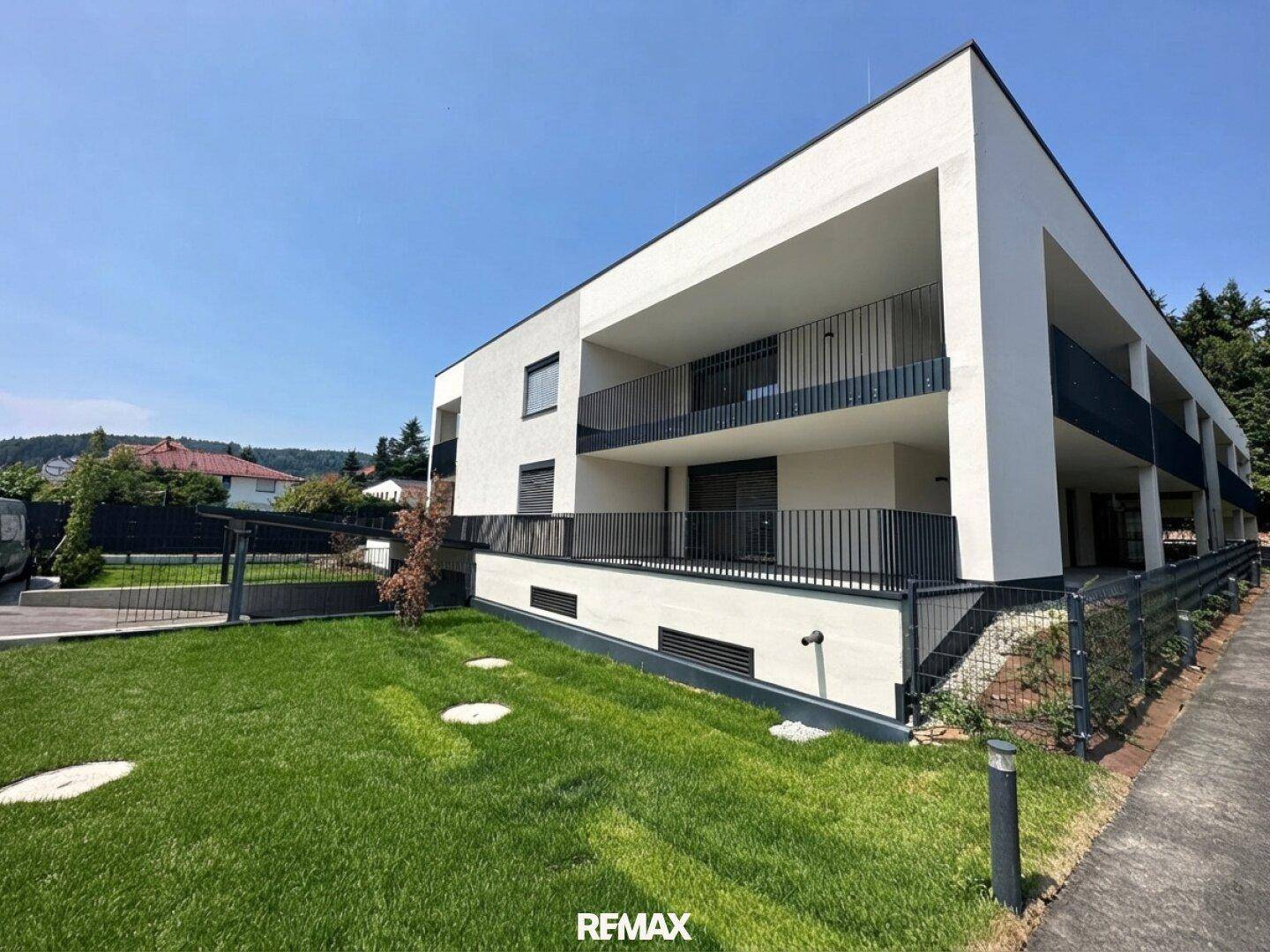 Modernes Apartmentgebäude mit klarer Architektur, Balkonen und gepflegter Rasenfläche.