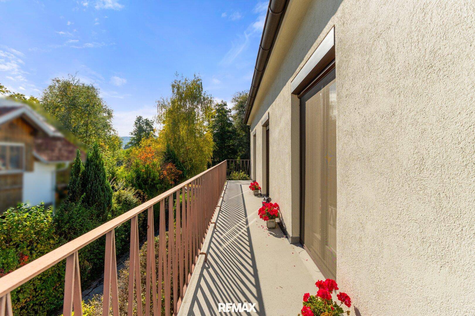 Langer Balkon mit Metallgeländer und Blumenkästen, bietet einen schönen Ausblick ins Grüne.