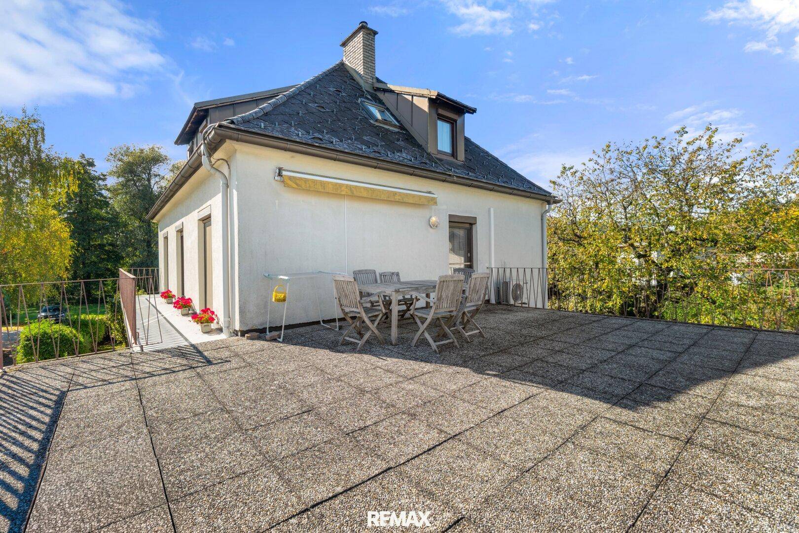 Geräumige Dachterrasse mit Fliesenboden und Holztischgruppe, ideal für Mahlzeiten im Freien.