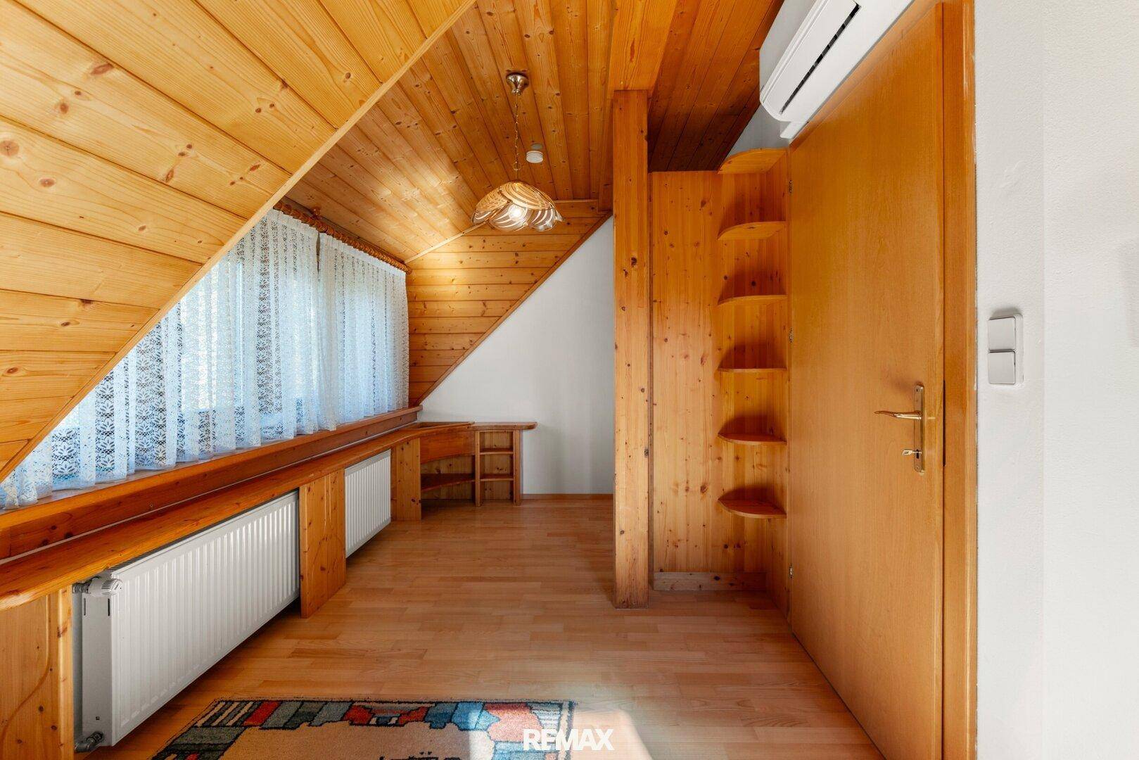 Dachgeschossraum mit Holzverkleidung, Fenster und Heizkörper, vielseitig nutzbar.