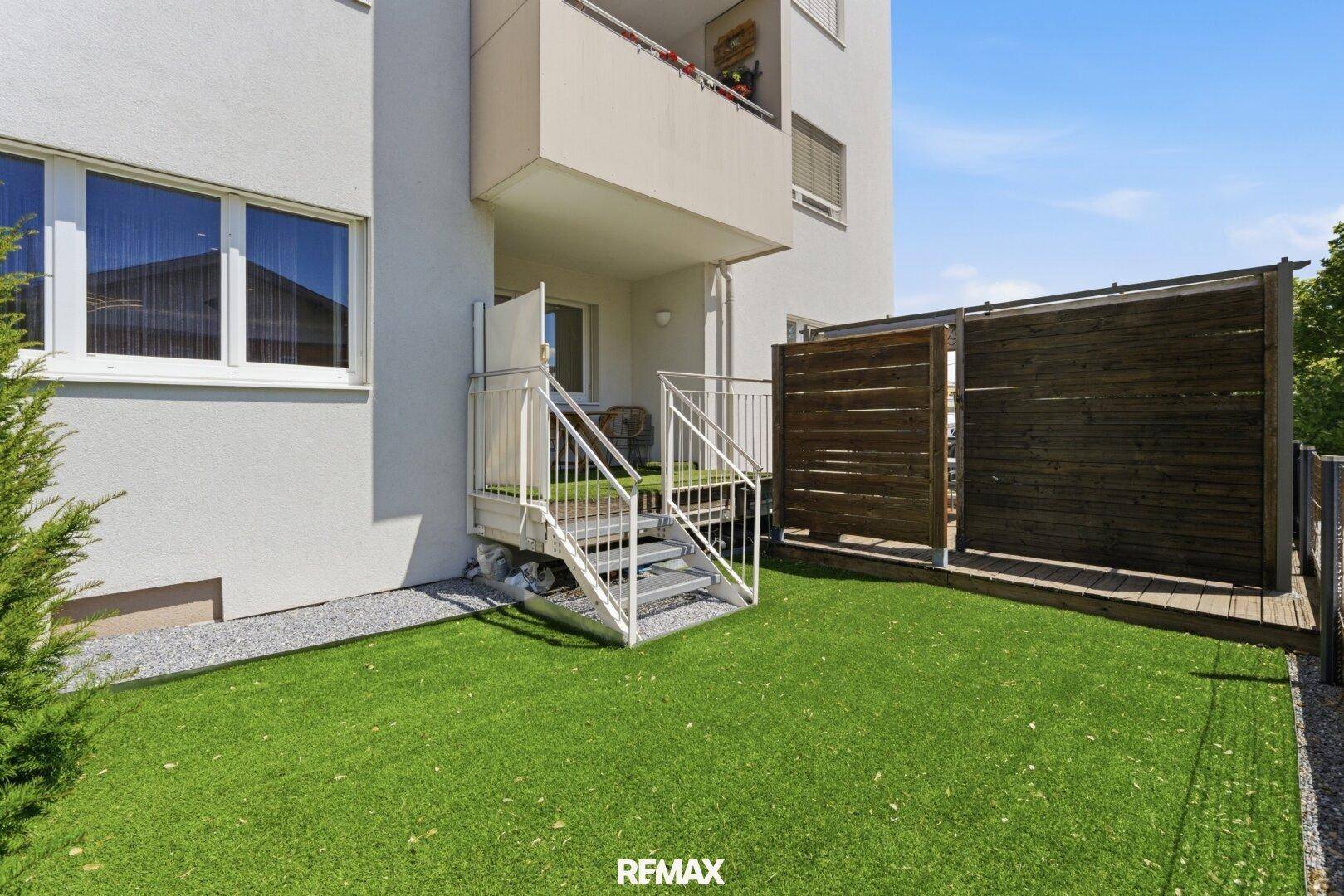 Kleiner Gartenbereich mit Kunstrasen, Sichtschutz und Treppe zum oberen Balkon.