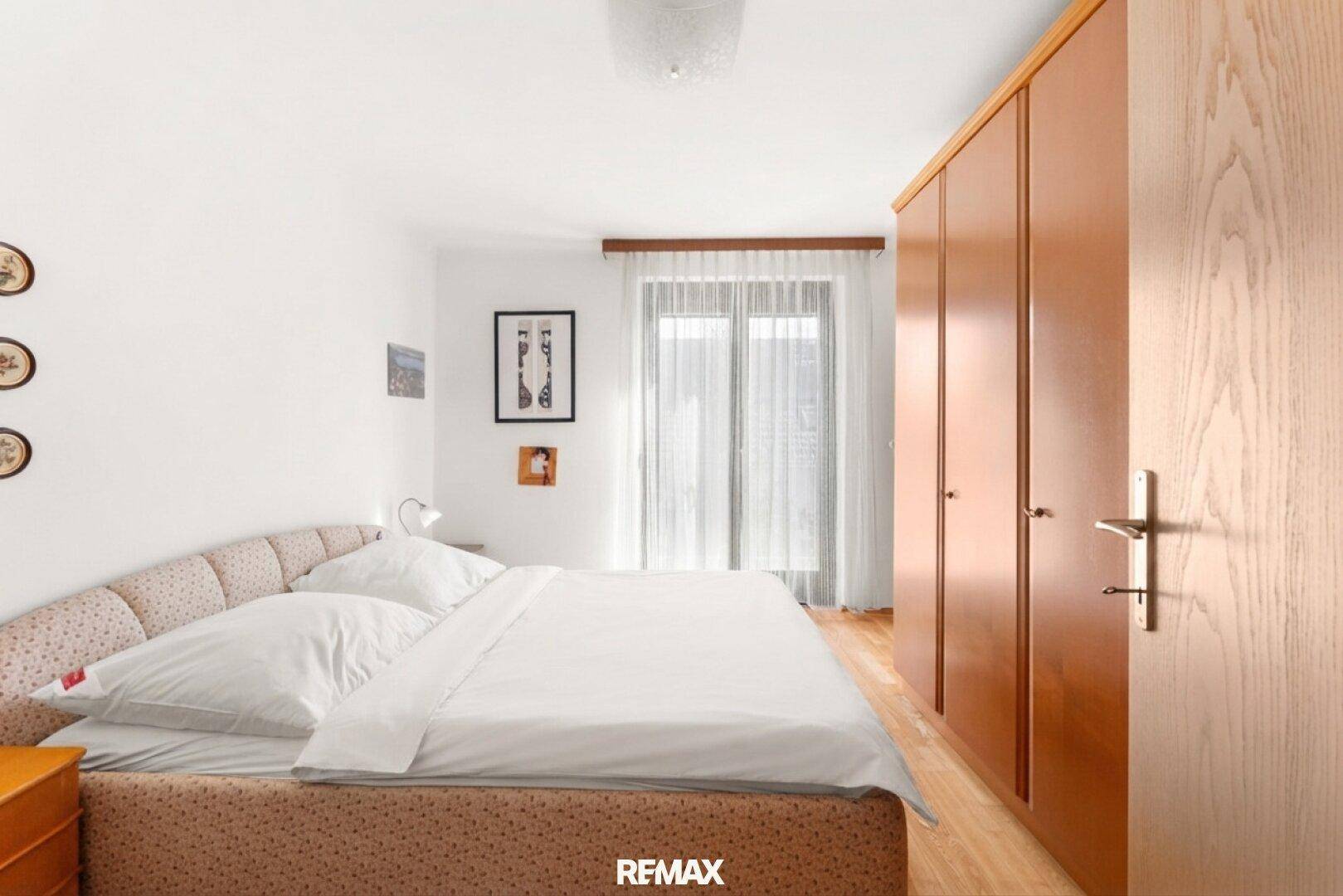Helles Schlafzimmer mit Doppelbett, großen Holzschränken und Zugang zum Balkon.