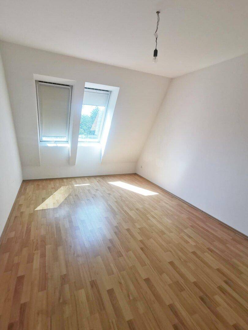Schlafzimmer im Dachgeschoss mit Holzboden und schrägen Wänden, hell und freundlich.