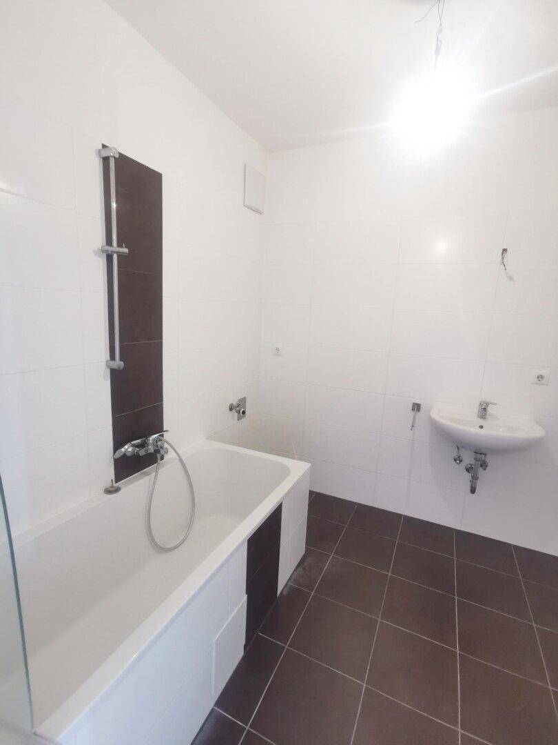 Helles Badezimmer mit Badewanne, Waschbecken und weißen Wandfliesen, gepflegt.