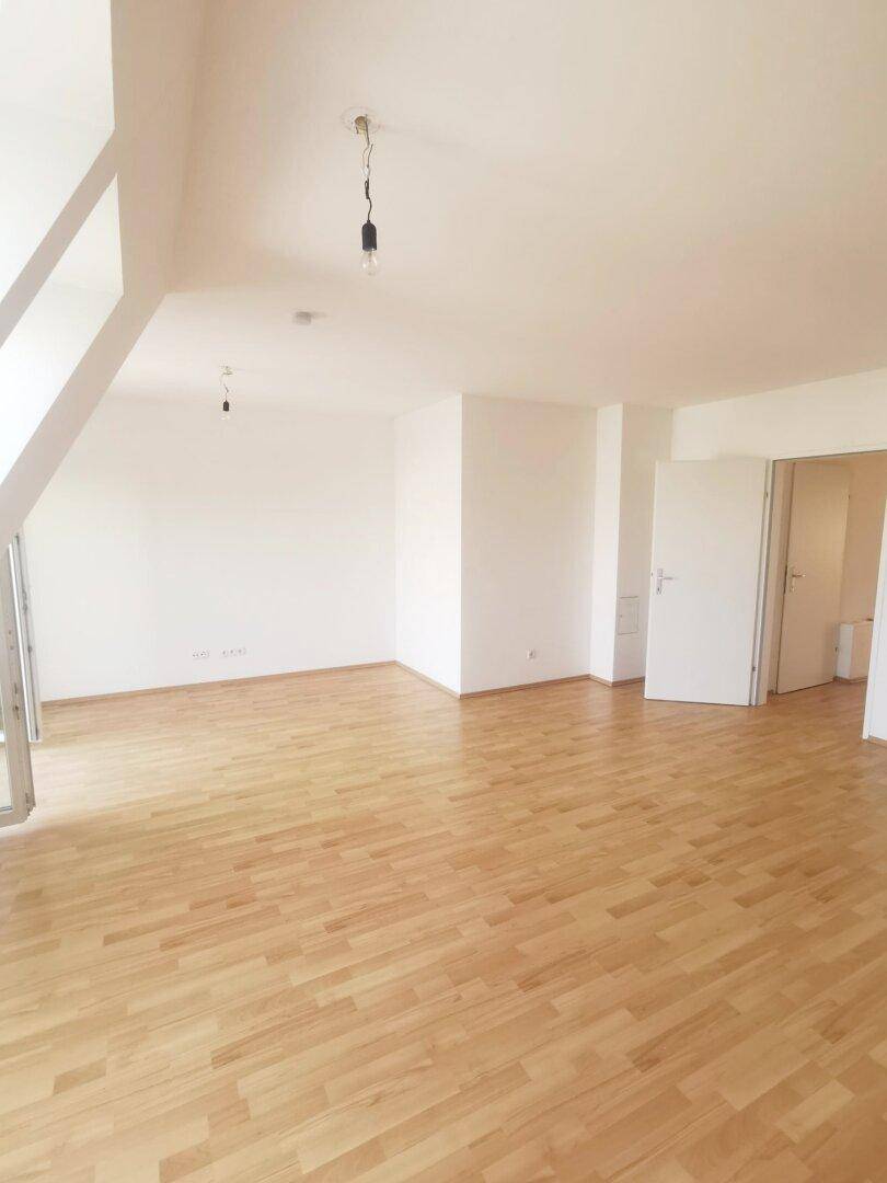 Großzügiges Wohnzimmer mit Holzboden und weißen Wänden, ideal für offene Gestaltung.