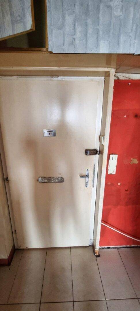 Eingangsbereich mit zwei Türen, eine davon in hellem Beige und die andere in Rot.