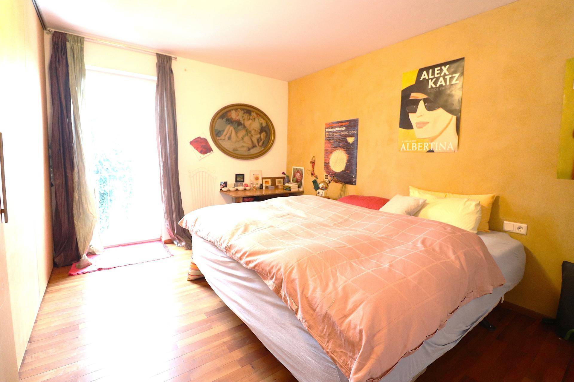 Schlafzimmer mit gelber Wand, Holzboden und Zugang zu einem Außenbereich.