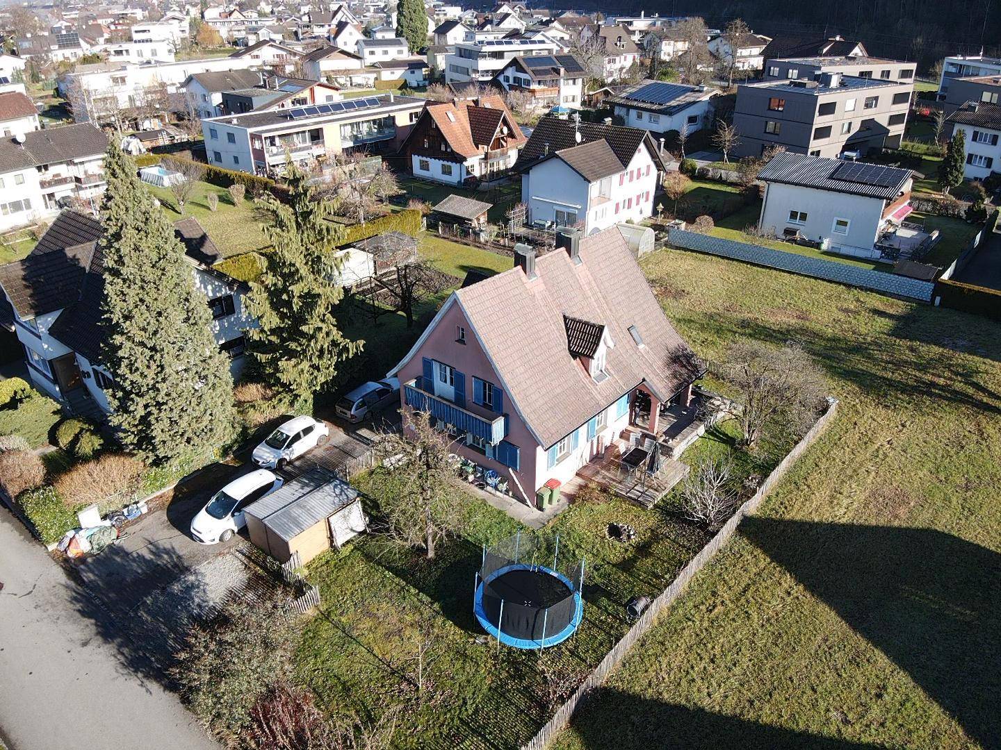 Vogelperspektive des Einfamilienhauses mit großem Garten, Trampolin und angrenzenden Grundstücken.