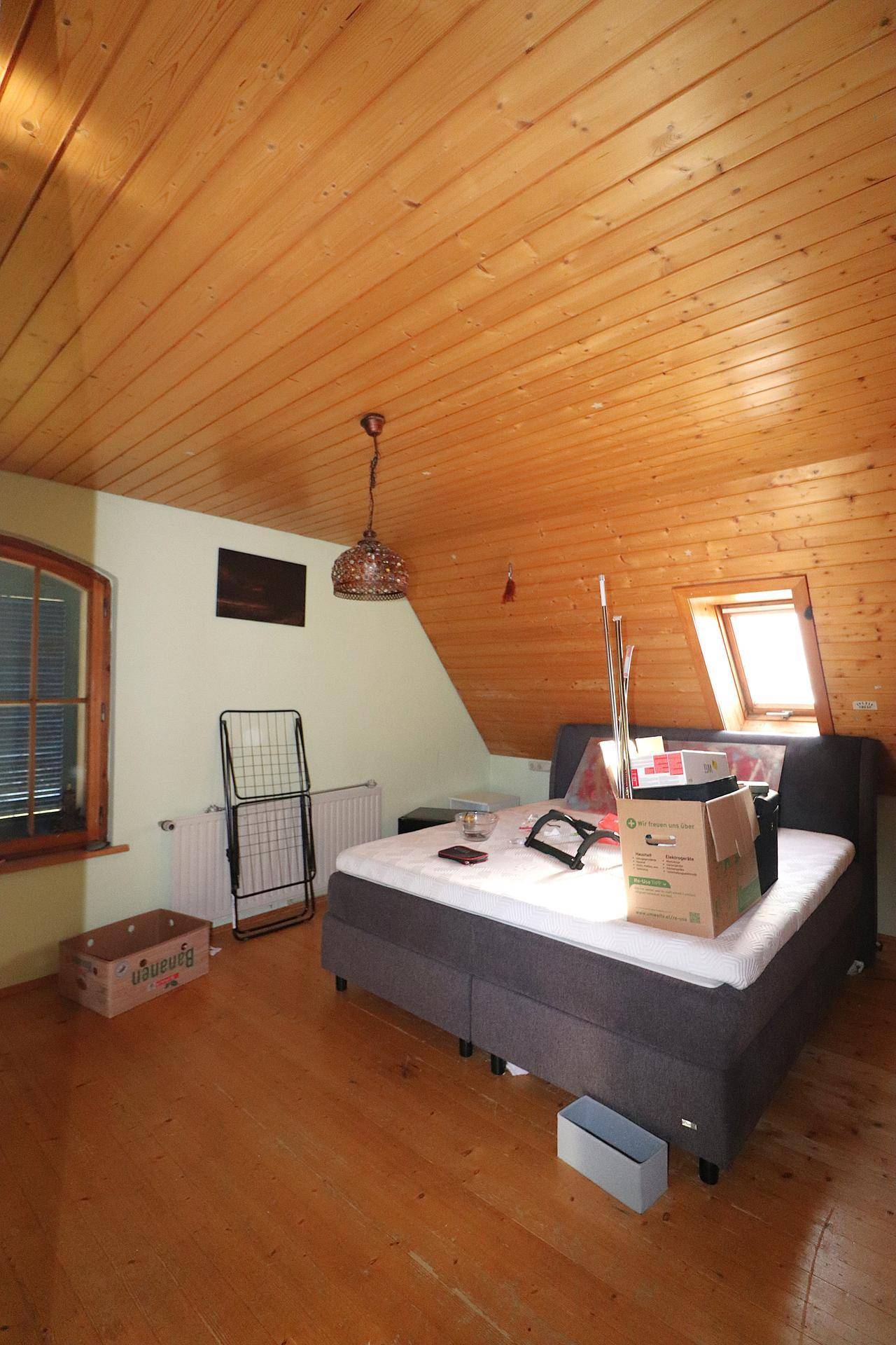 Schlafzimmer im Dachgeschoss mit Holzboden, Dachschrägen und natürlichem Lichteinfall.