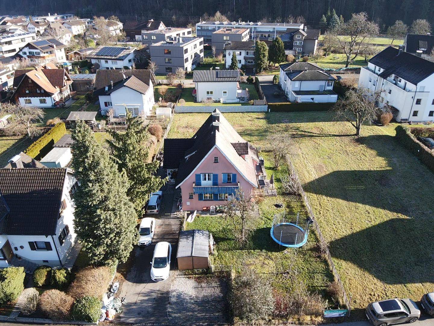 Luftaufnahme des Hauses mit Garten, Trampolin und angrenzenden unbebauten Flächen.