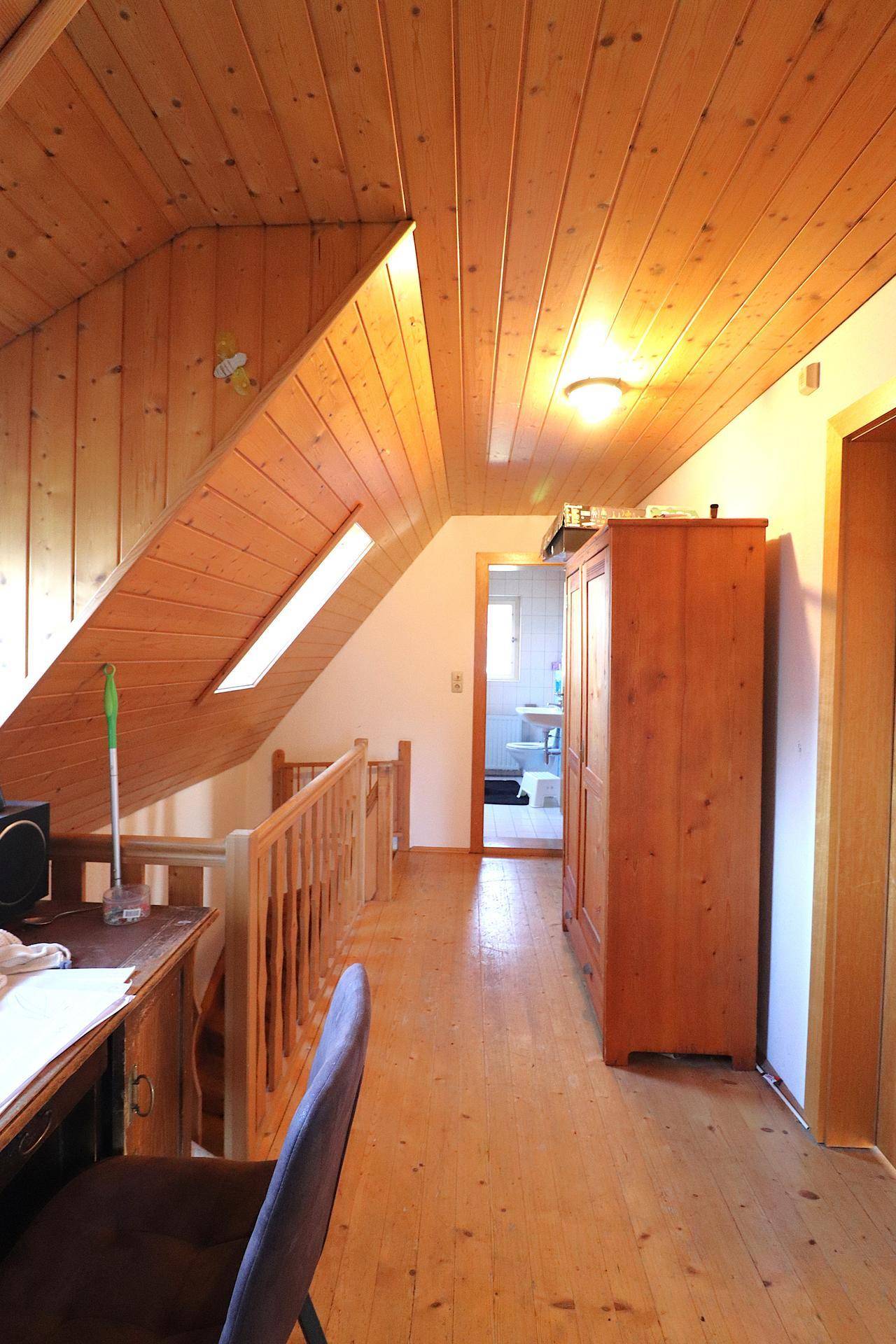 Dachgeschossflur mit Holzschrank, Holzboden und Zugang zu weiteren Zimmern.