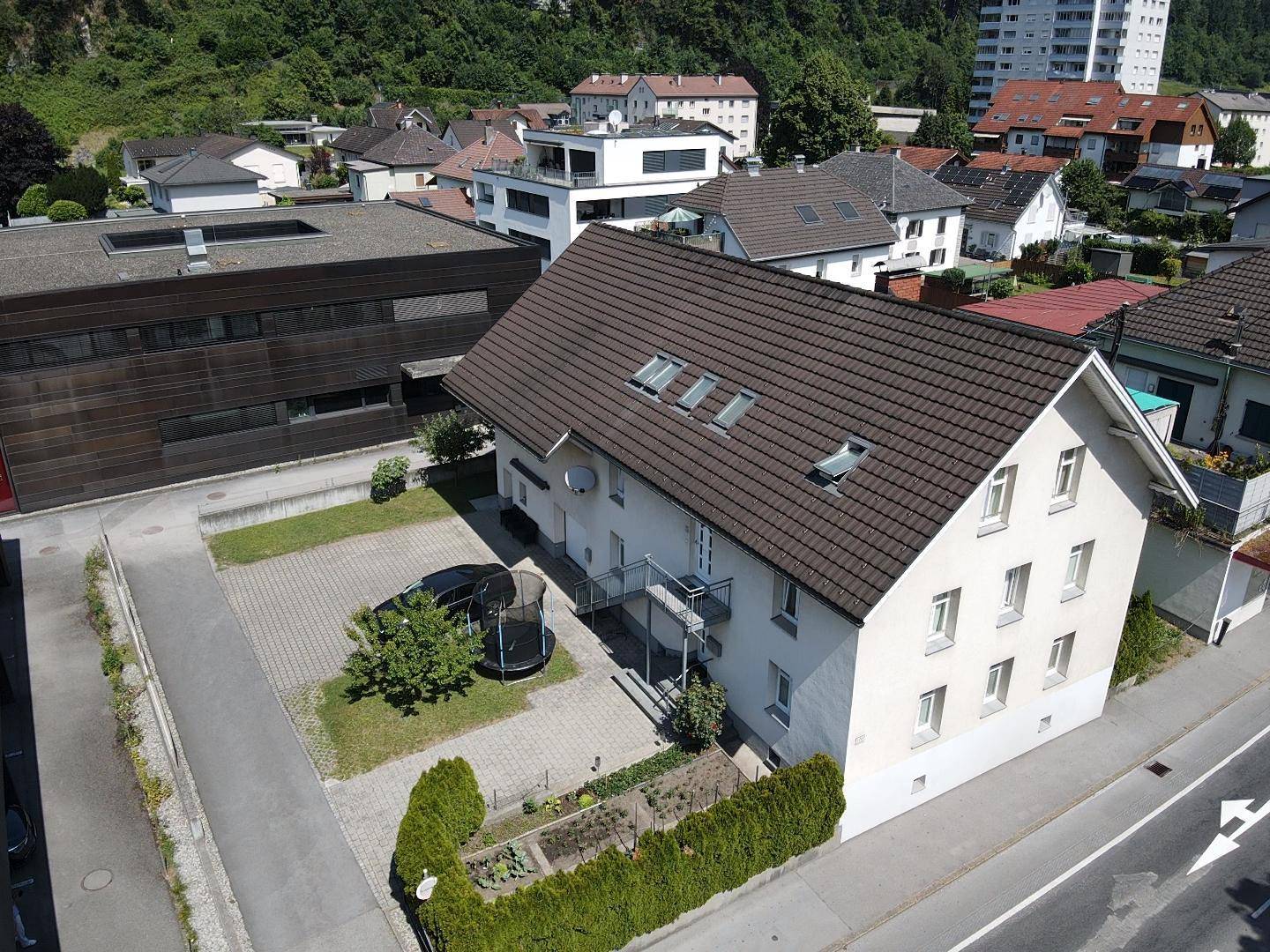 Luftaufnahme des Hauses mit umliegenden Gebäuden, Parkplatz und Trampolin im Gartenbereich.