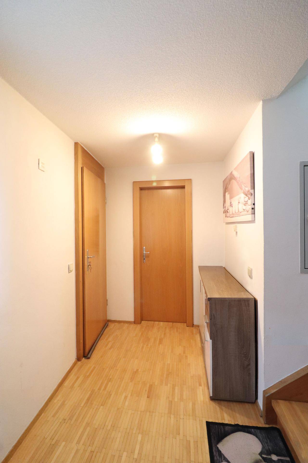 Eingangsbereich mit Holzboden, Garderobenmöbeln und Türen zu weiteren Räumen.
