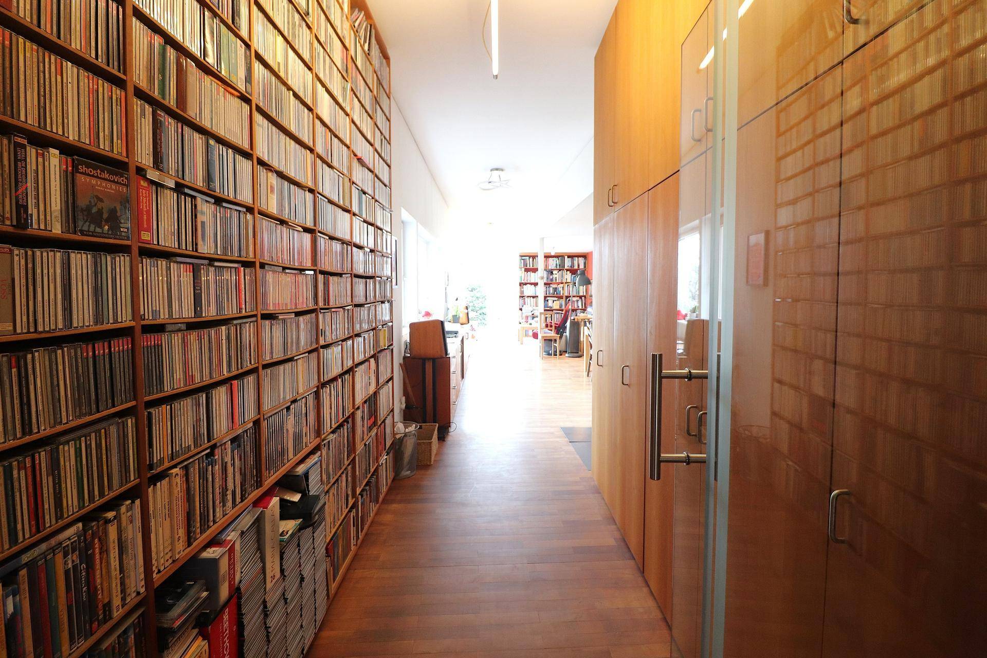 Langer Flur mit raumhohen Bücherregalen und Holzverkleidung, der viel Stauraum bietet.