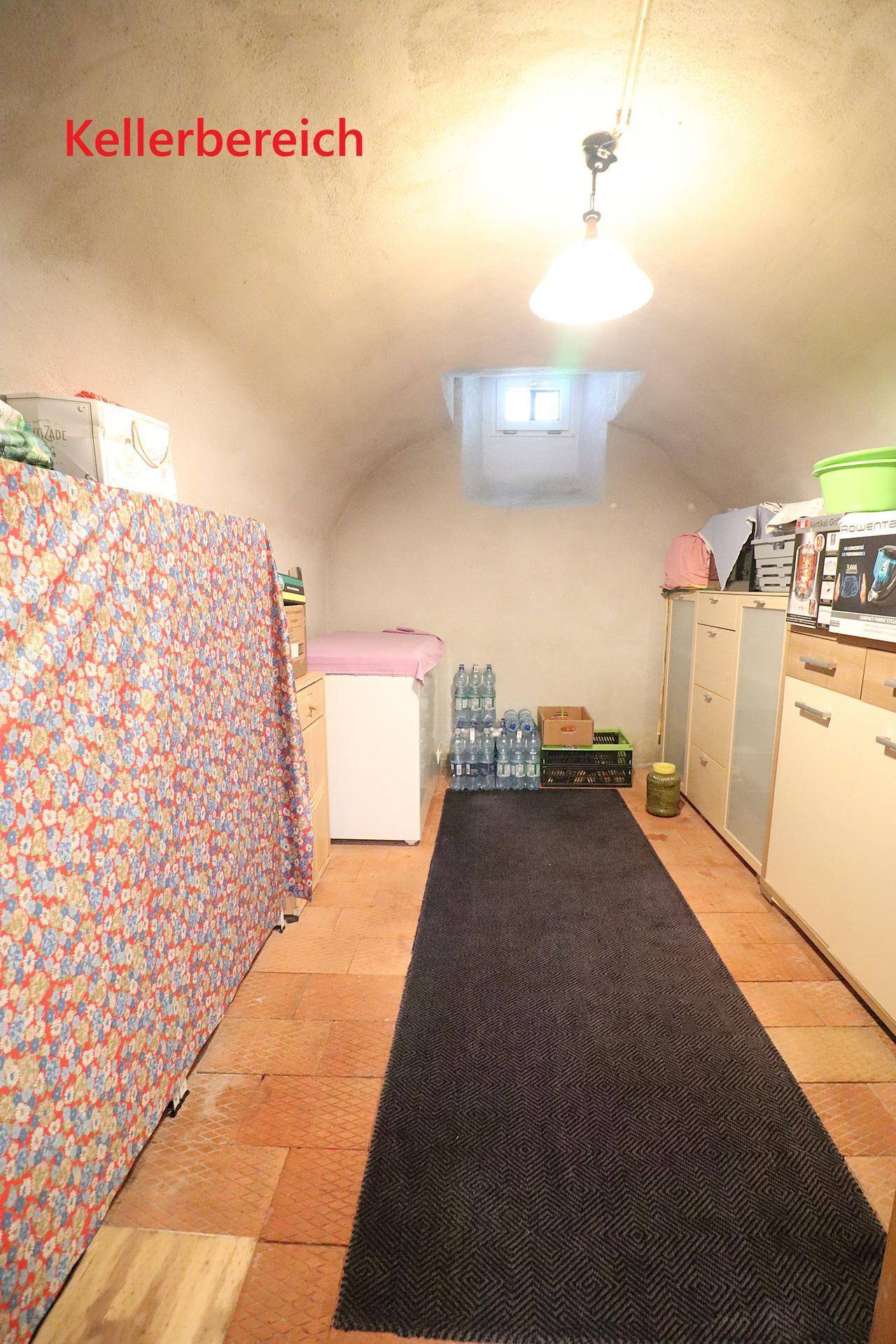 Kellerbereich mit gewölbter Decke, Fliesenboden und verschiedenen Lagerregalen.