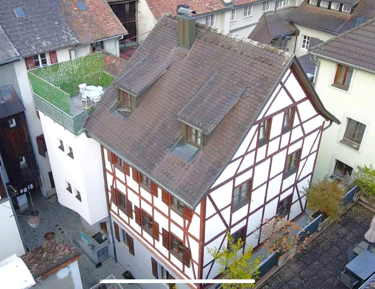Historisches Fachwerkhaus mit markanter Architektur, Dachterrasse und umliegenden Gebäuden.