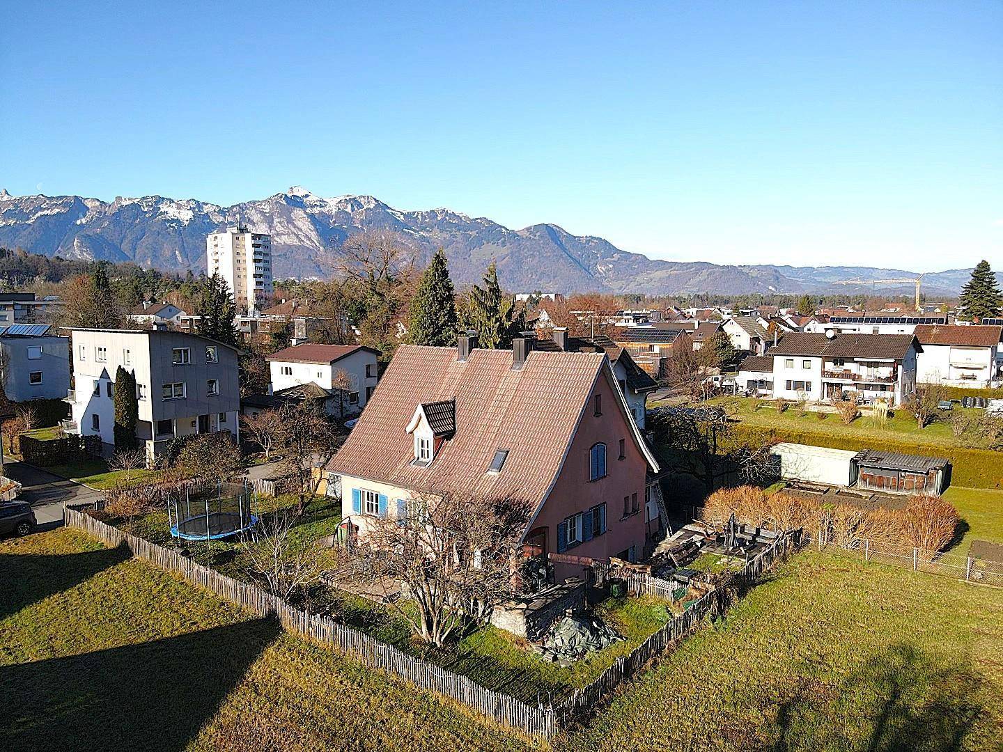 Weitläufige Luftaufnahme des Hauses mit Garten und beeindruckendem Bergpanorama im Hintergrund.