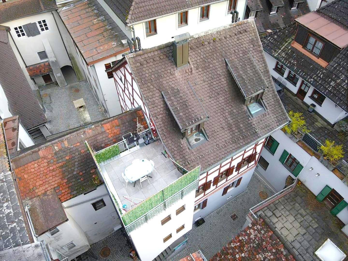 Luftaufnahme eines historischen Gebäudes mit Dachterrasse und umliegenden Häusern.