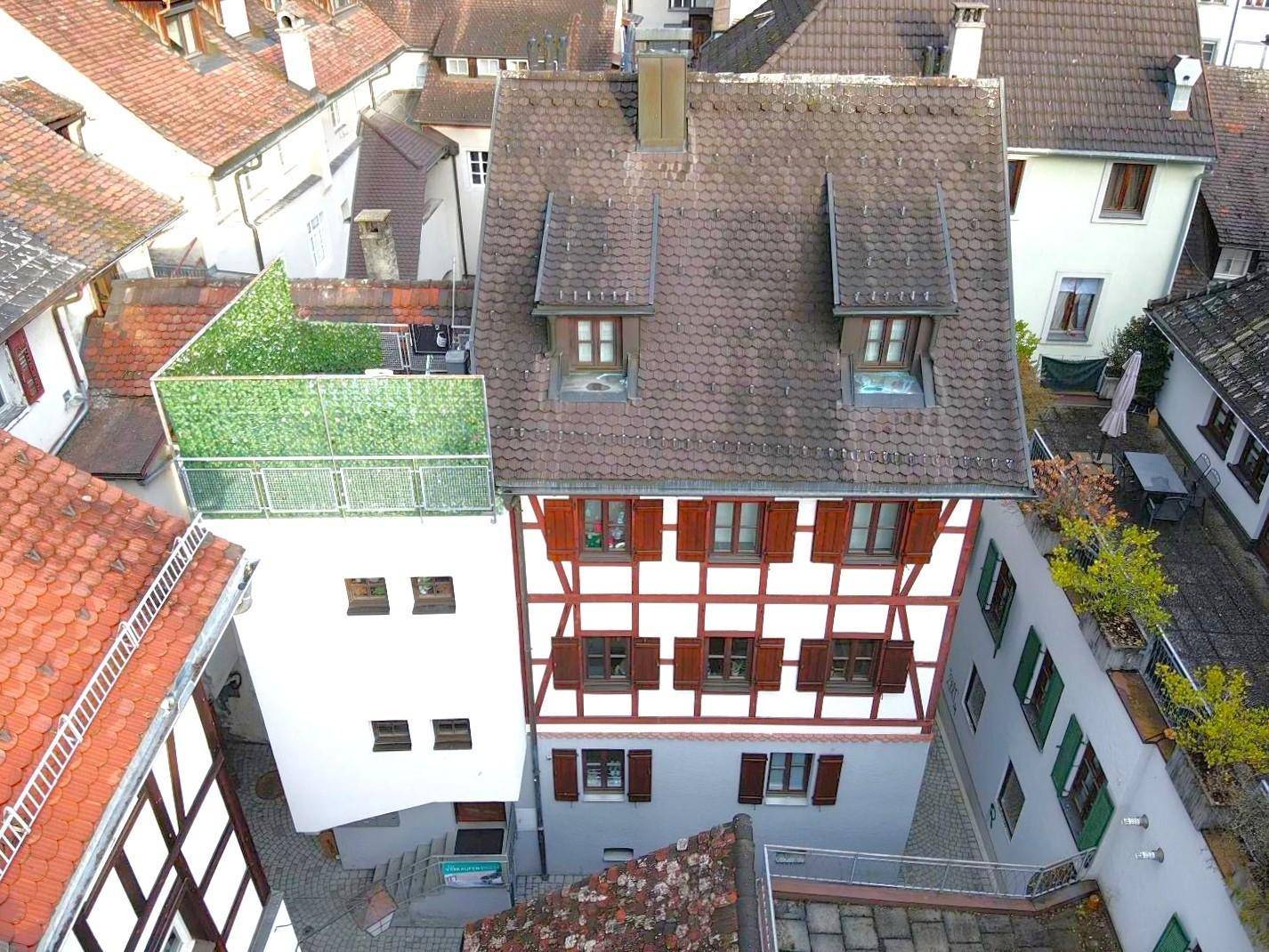 Vogelperspektive eines Fachwerkhauses mit Dachterrasse und traditionellen Fensterläden.