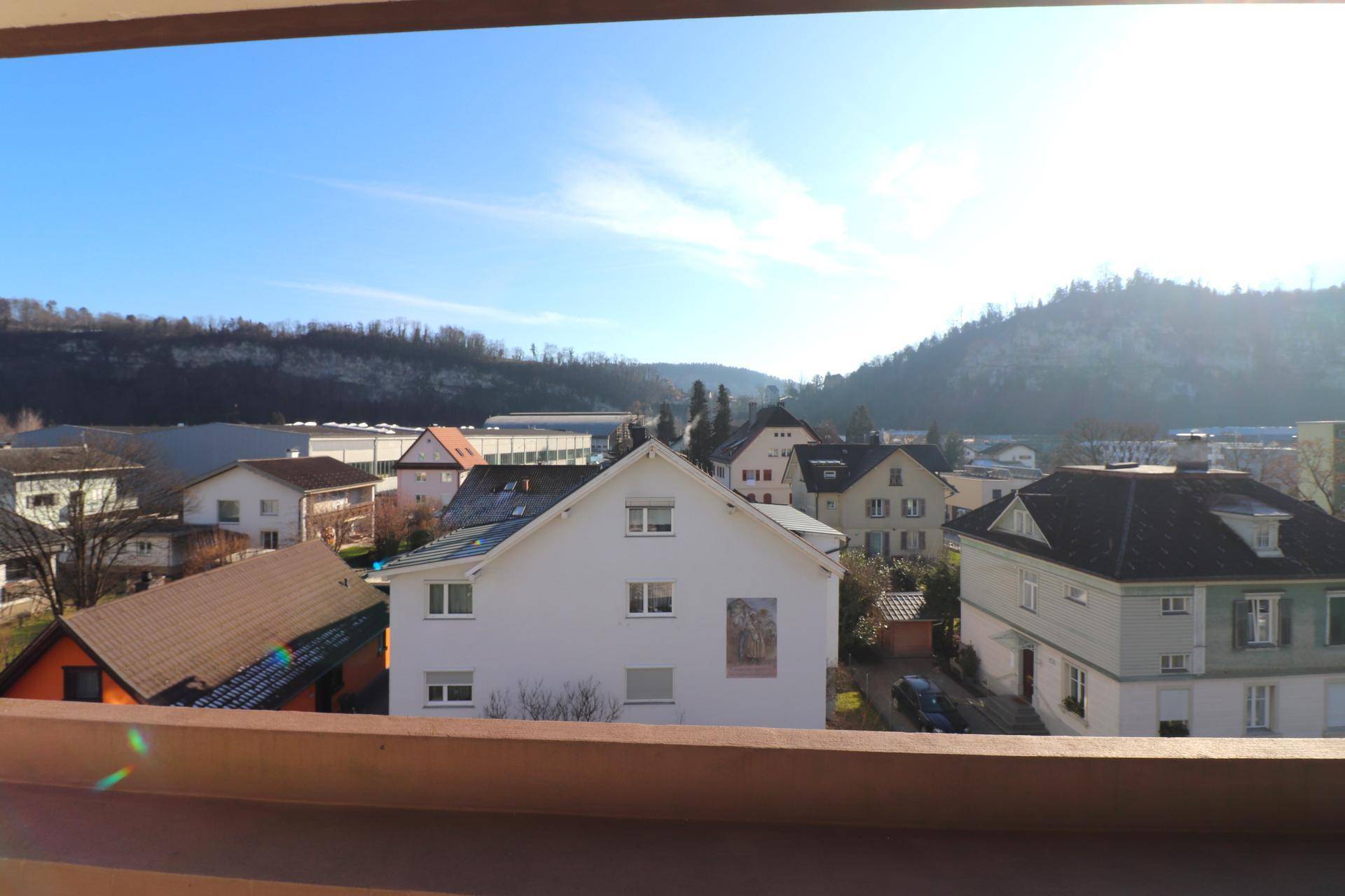 Weitblick über die umliegende Wohngegend und bewaldete Hügel unter blauem Himmel.