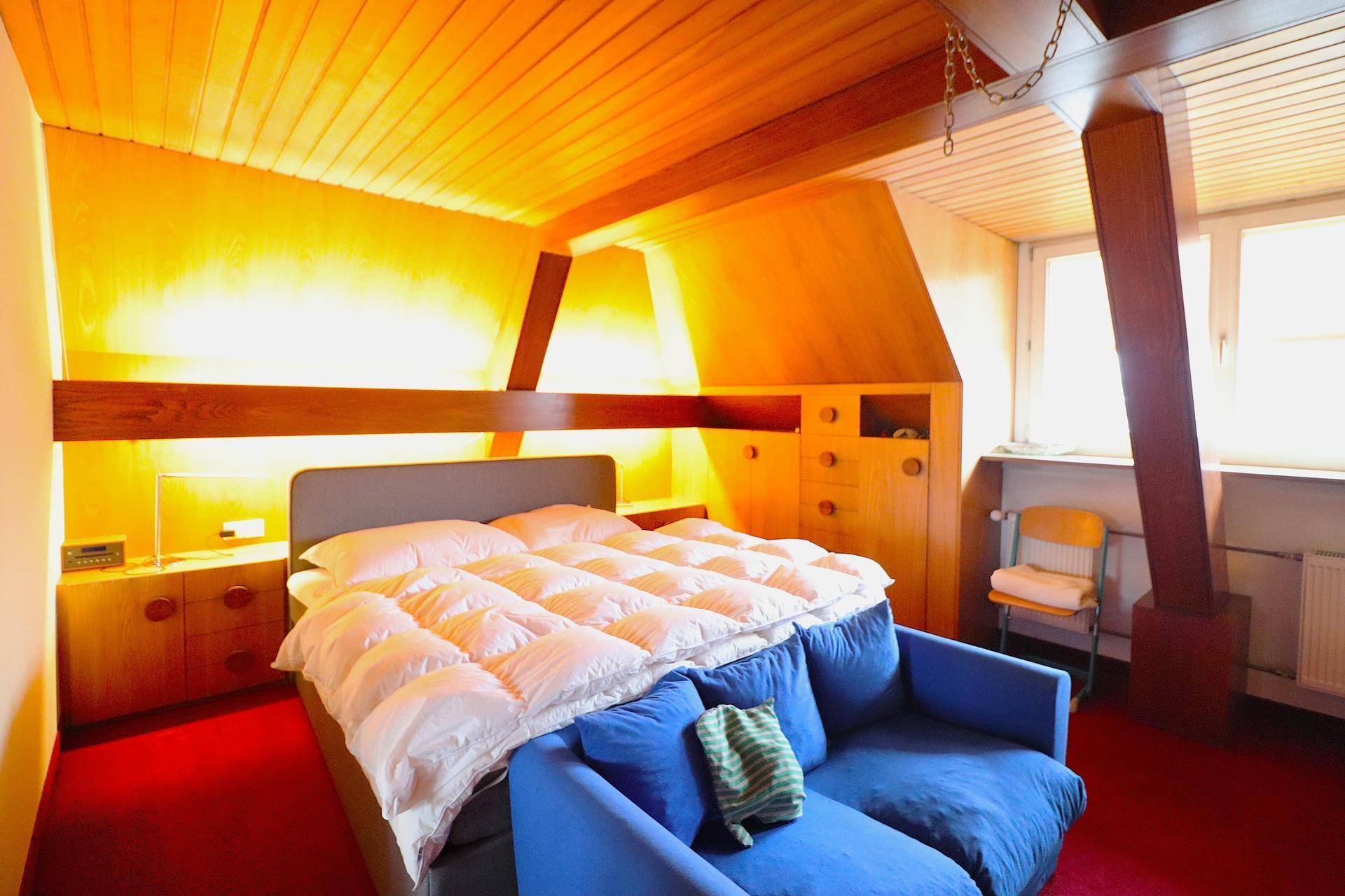 Dachschlafzimmer mit Holzbalken, Holzdecke und gemütlicher Atmosphäre.