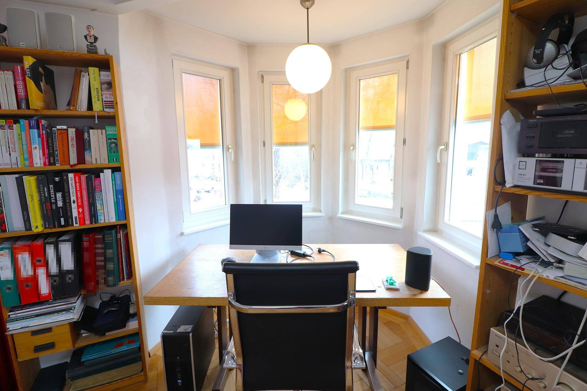 Heller Arbeitsbereich mit Schreibtisch, Bücherregalen und großen Fenstern für viel Tageslicht.