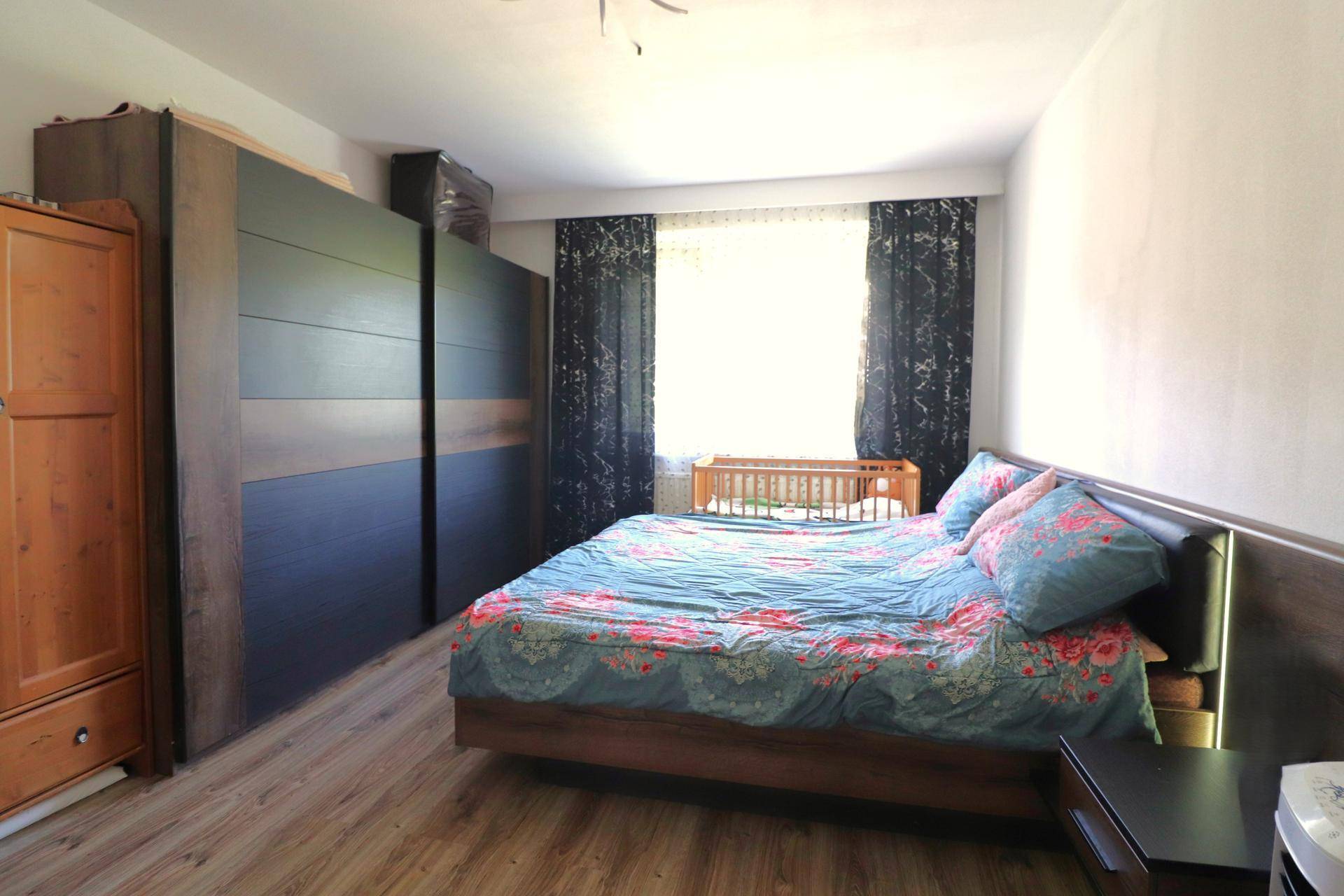 Schlafzimmer mit großem Bett, Kleiderschrank und Holzboden, ideal für eine Familie.