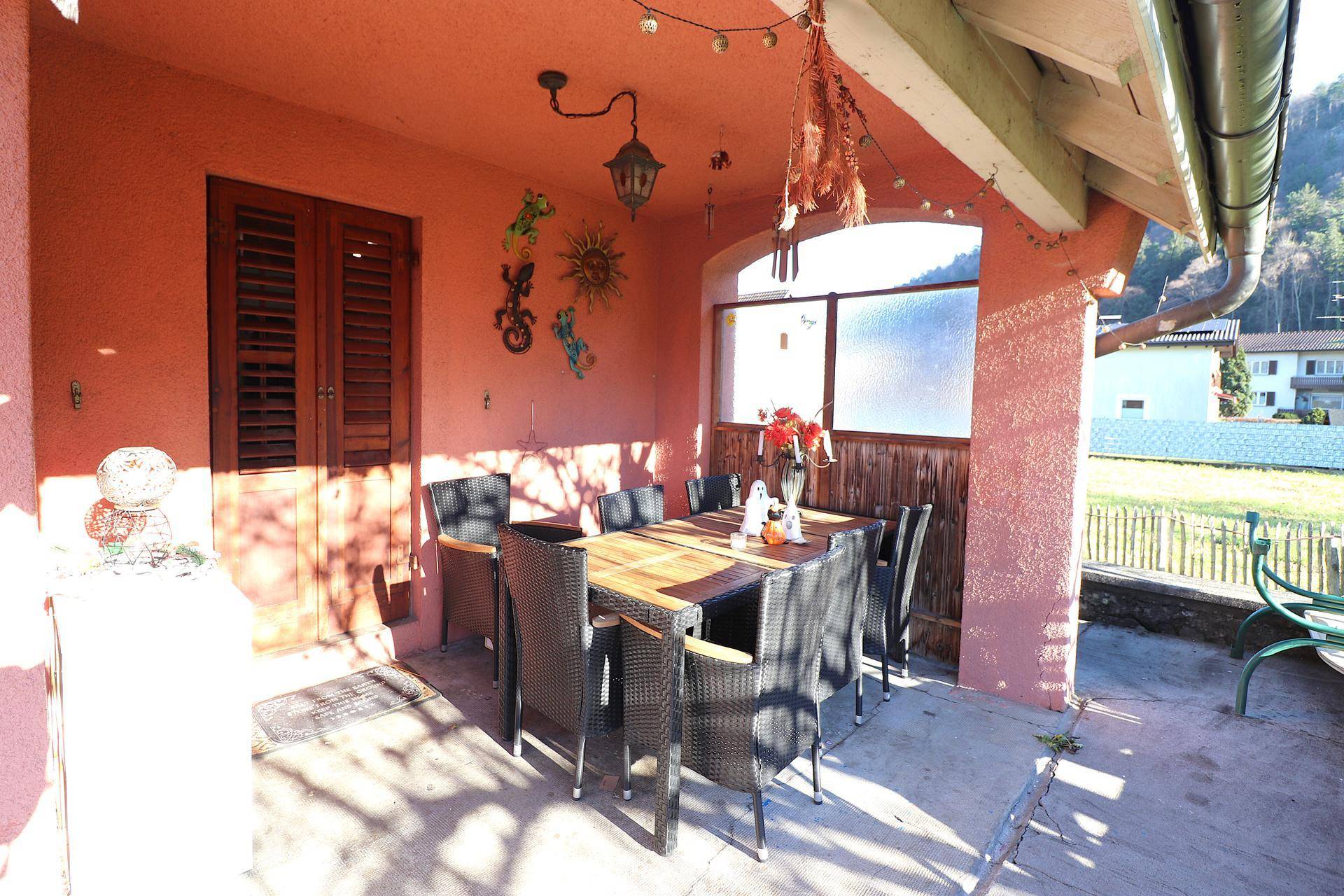 Überdachte Terrasse mit Esstisch und Stühlen, ideal für Mahlzeiten im Freien.