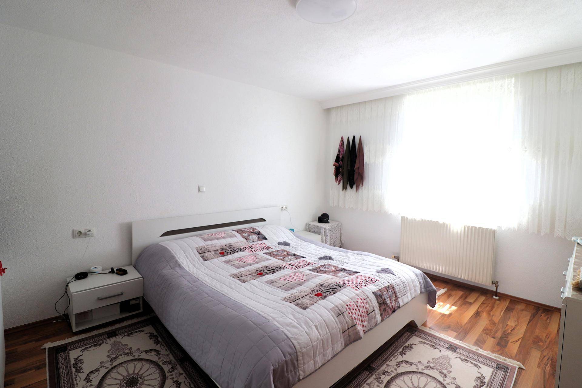 Schlafzimmer mit Doppelbett, Holzboden und großem Fenster für viel Tageslicht.