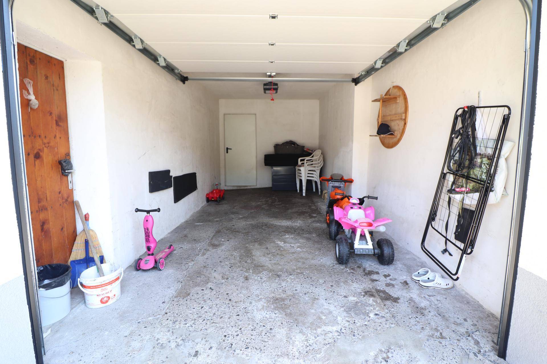 Geräumige Garage mit Betonboden, Stauraum und Platz für Fahrzeuge oder Spielzeug.
