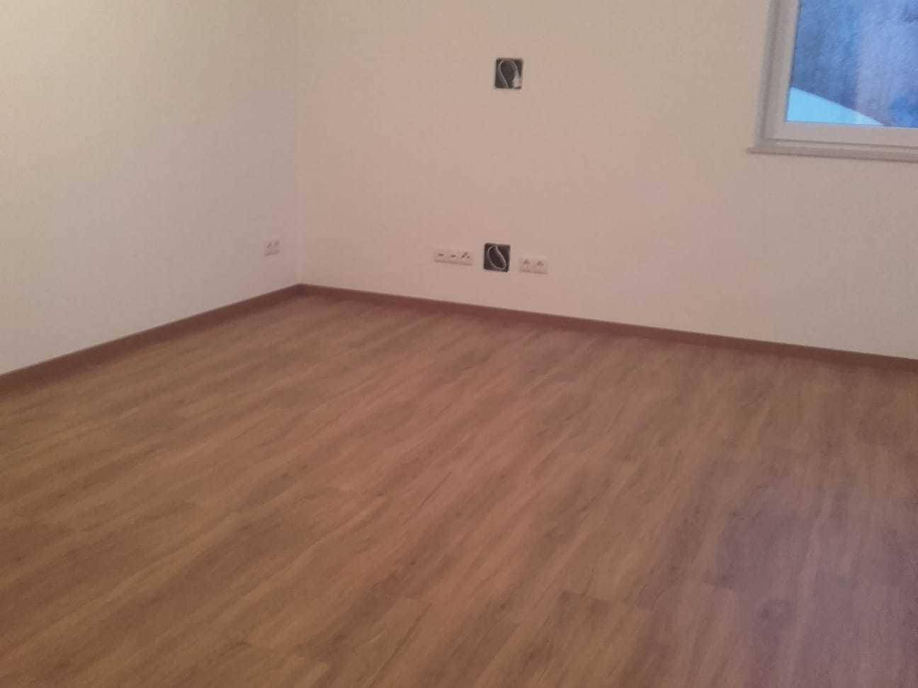 Leerer Raum mit hellem Laminatboden und weißen Wänden, bereit zur individuellen Gestaltung.