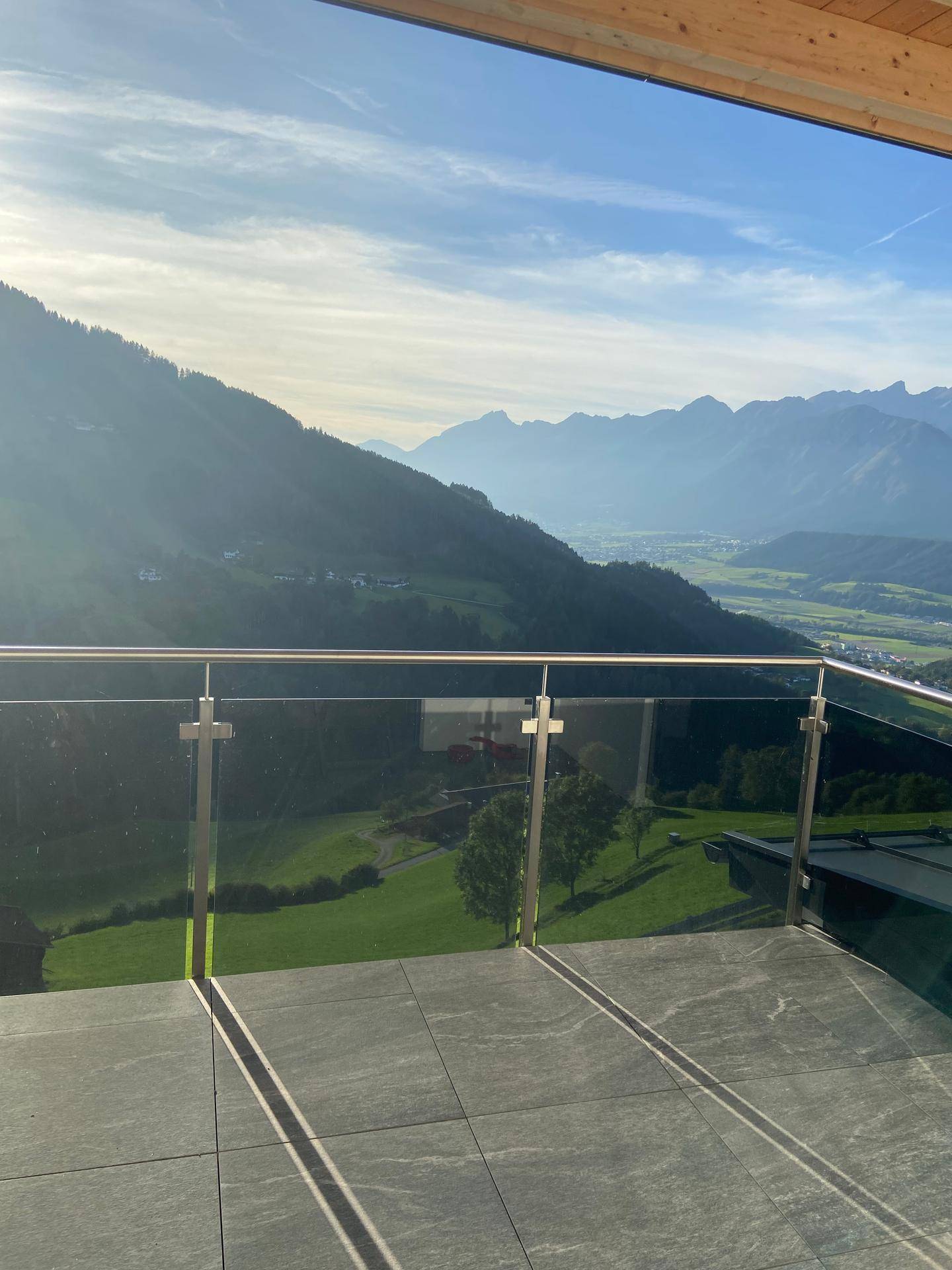 Großer Balkon mit Glasgeländer und atemberaubendem Panoramablick auf die umliegende Bergwelt.