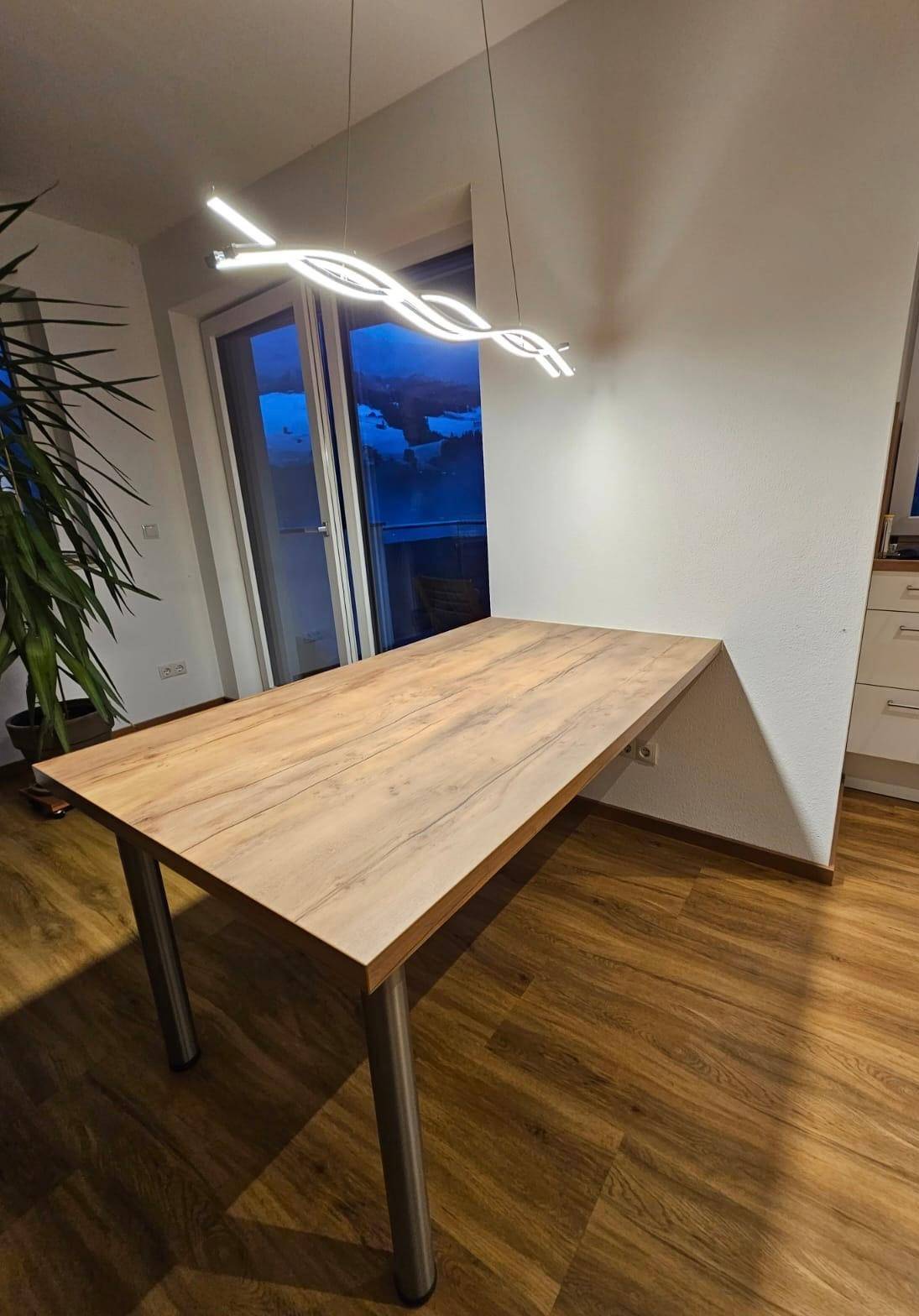 Essbereich mit modernem Esstisch, Designer-Pendelleuchte und Zugang zu einem Außenbereich.