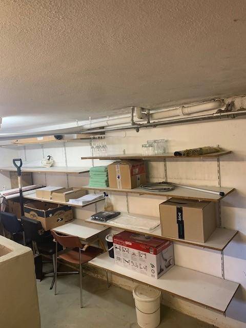 Kellerraum mit Regalen voller Kartons und Gegenständen, sichtbaren Rohren an der Decke.
