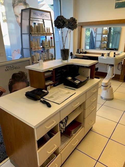 Empfangsbereich eines Friseursalons mit einem weißen Tresen, Telefon und einem Produktregal im Hintergrund.