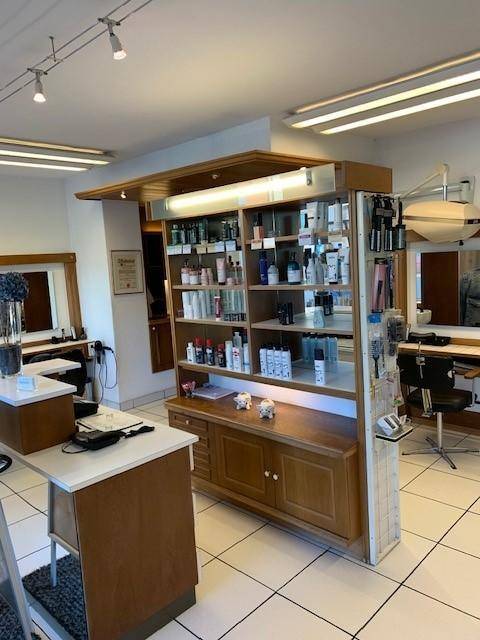 Innenansicht eines Friseursalons mit einem großen Holzregal für Produktpräsentationen und weißen Fliesen.