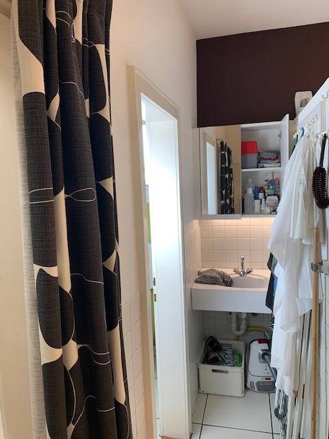 Kleiner Waschbereich mit einem Waschbecken, Spiegelschrank und weißen Fliesen an den Wänden.
